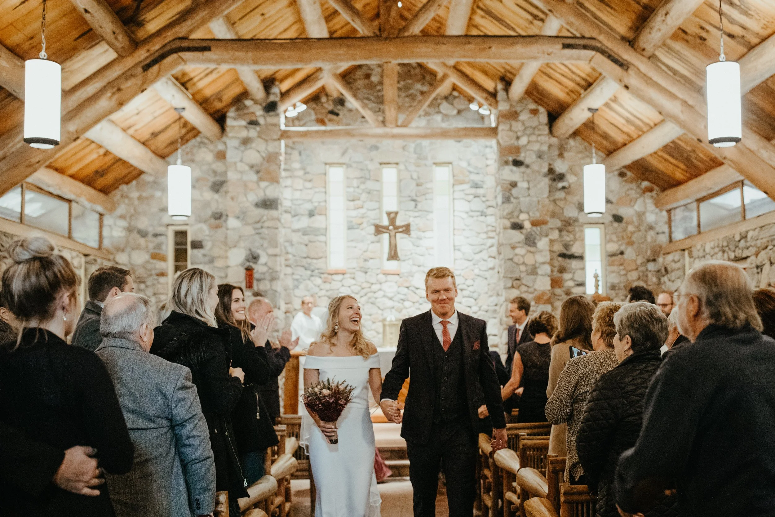 Bride and Groom smiling after wedding ceremony in coblestone chapel at Camp Foley in Pine River, Minnesota