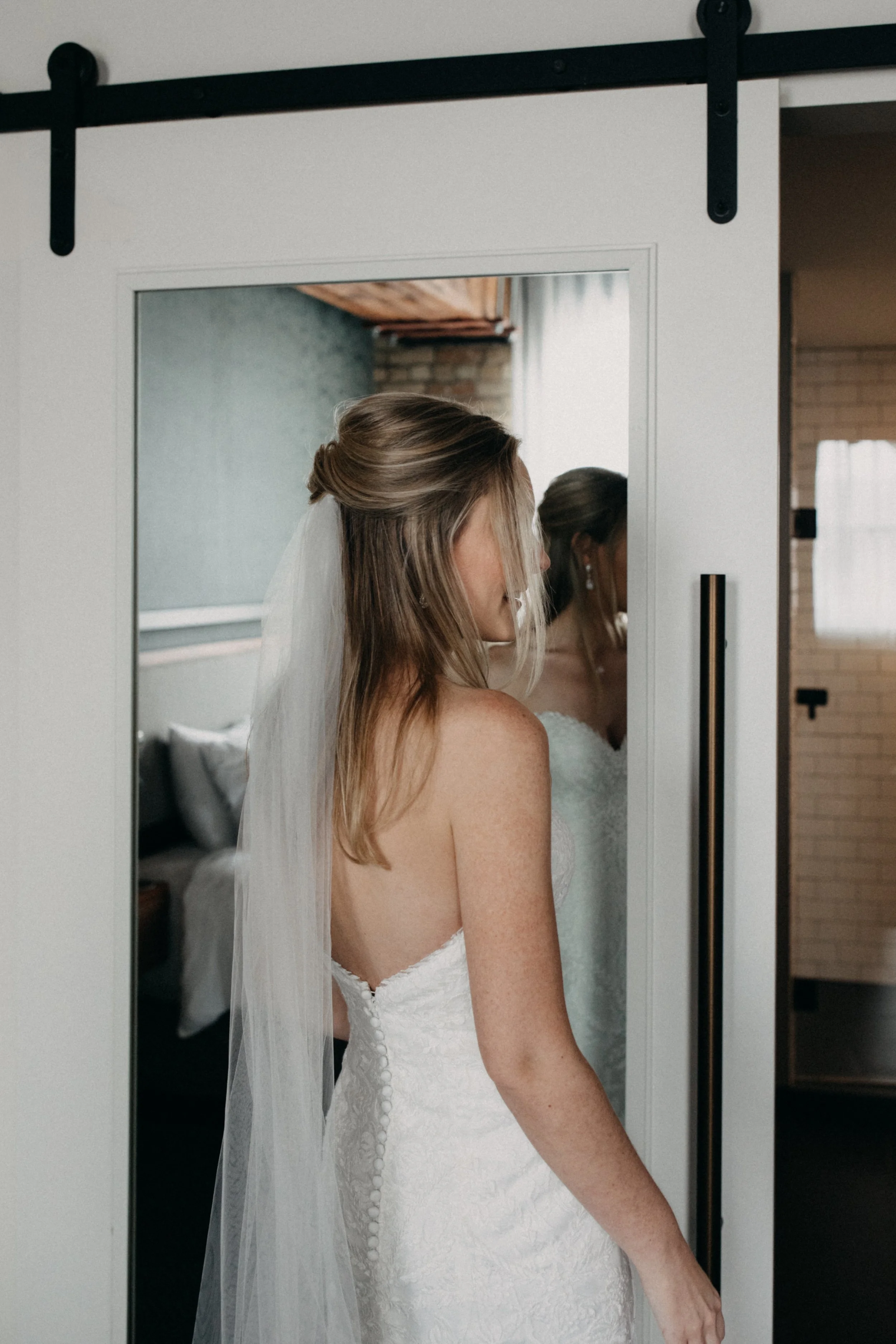 Bride getting ready at the Hewing Hotel with mirror reflection of her earring