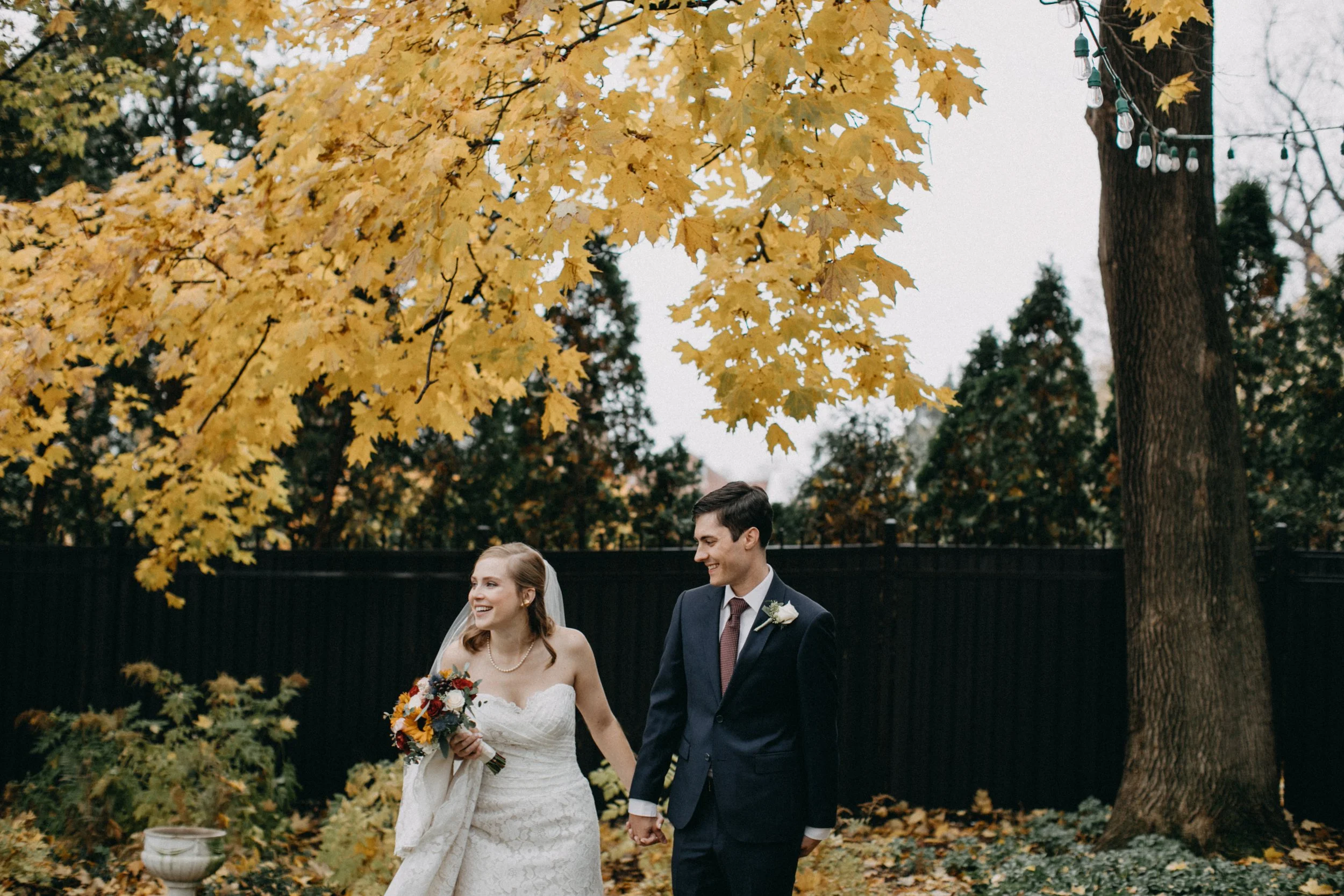 Bride and groom standing under maple tree in the fall at their St Paul College Club wedding