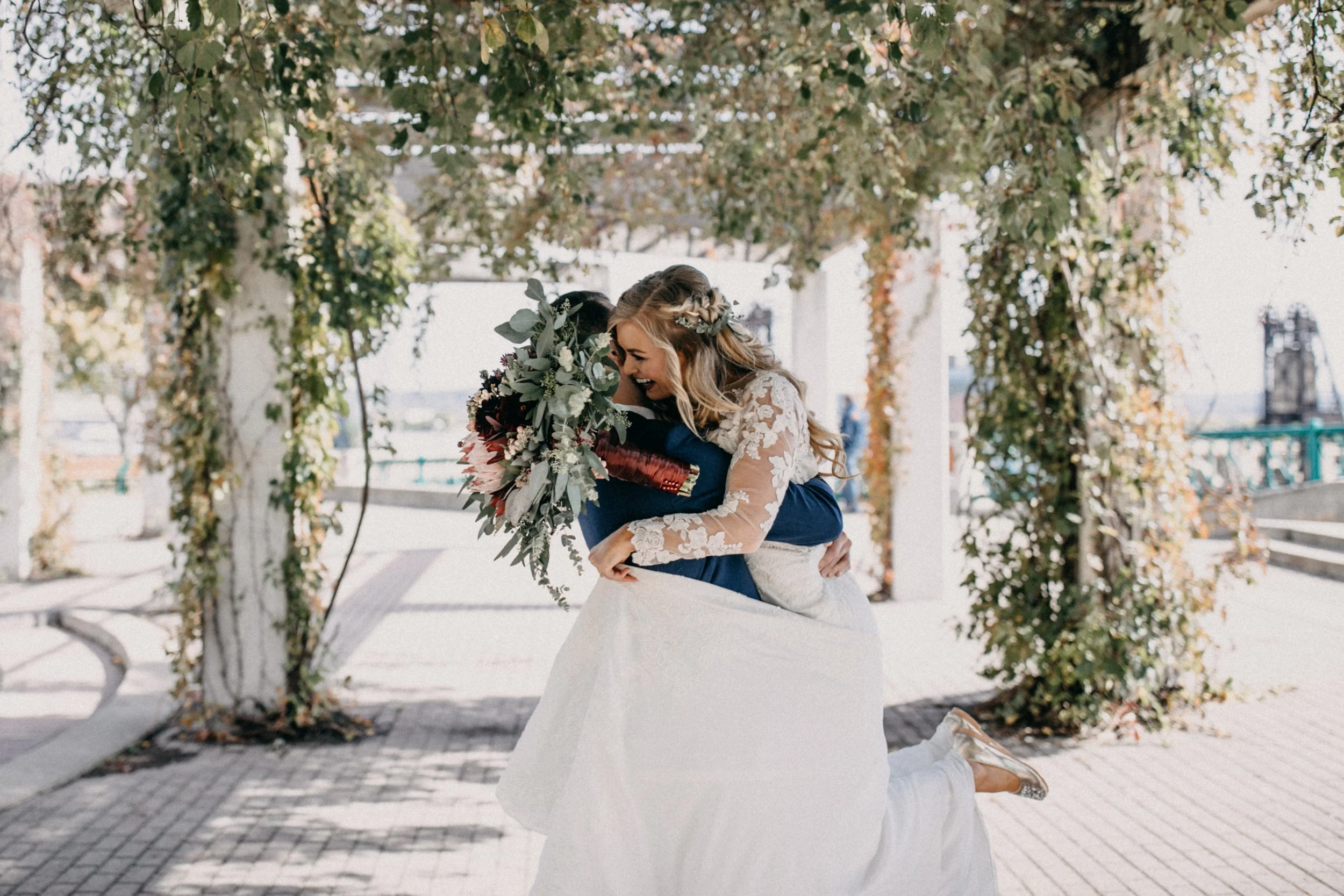Groom spinning bride under ivy covered pergola at St Paul, Minnesota wedding