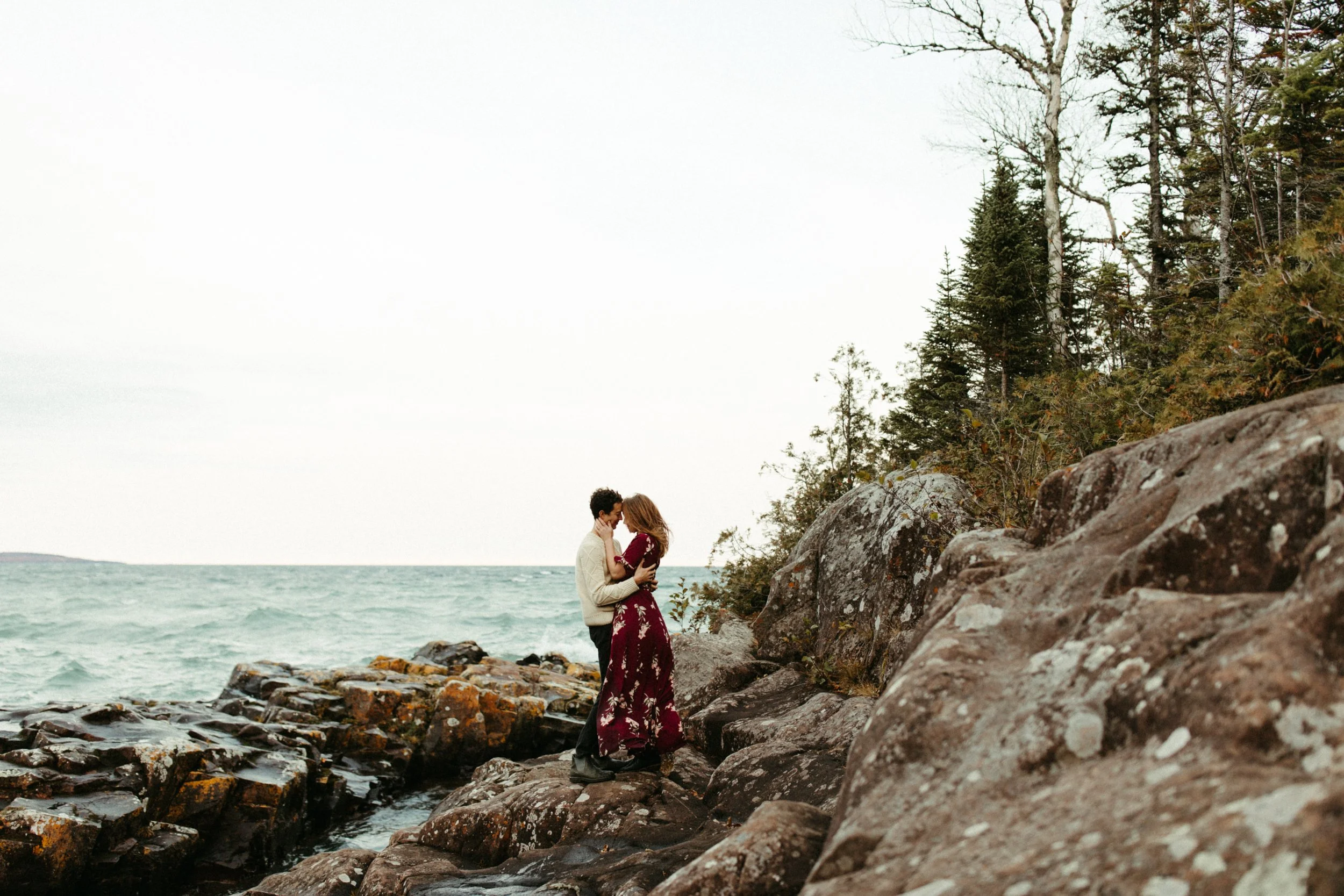 Engaged couple standing in rocky point of Artist Point in Grand Marais, Minnesota