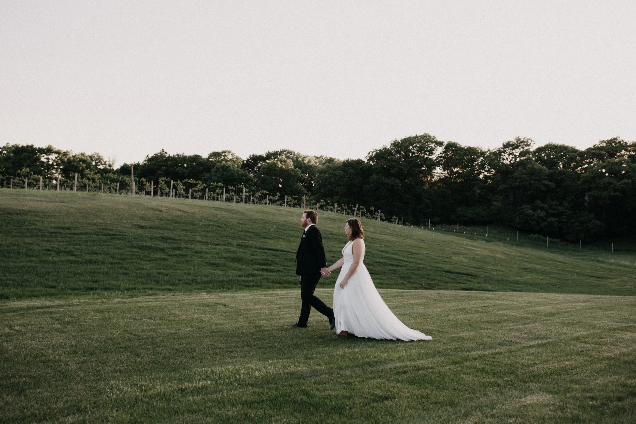 Bride and groom walking in front of Vineyard at 7 vines winery wedding