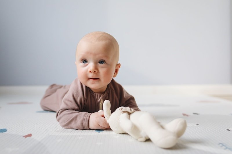Bébé placé sur le ventre, sur un tapis de sol : favoriser la motricité du bébé