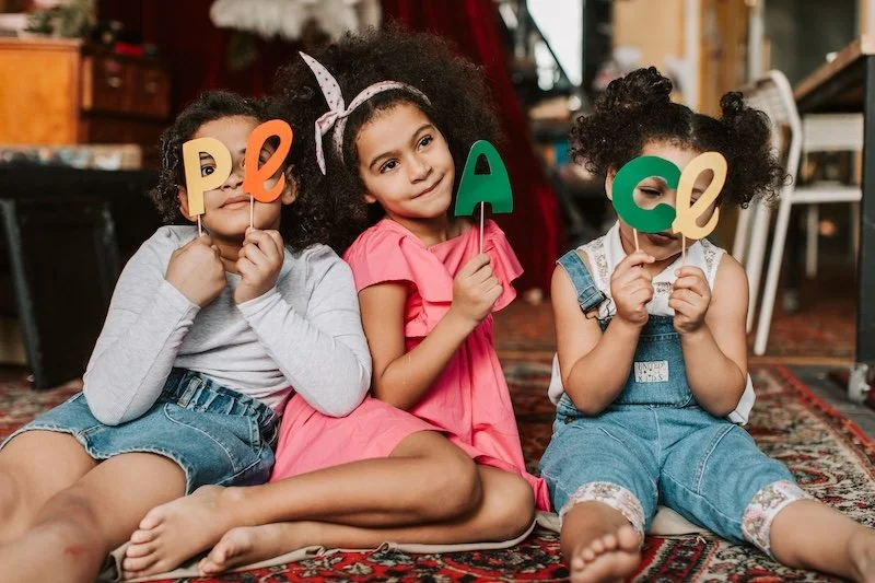 Changer de regard sur l'enfance : 3 enfants qui composent le mot Peace avec des lettres découpées.