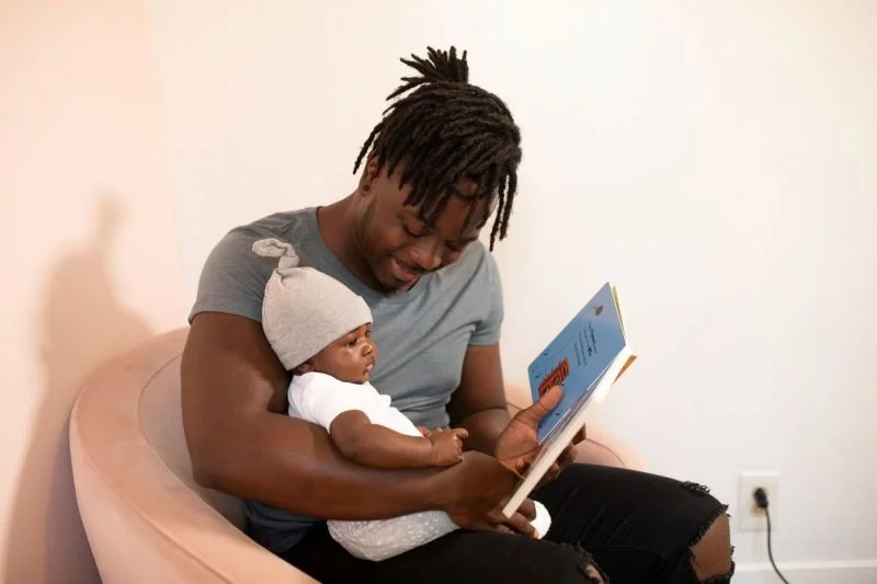 Lire aux bébés : de nombreux bienfaits pour son développement, son langage et la relation que l'on tisse avec lui. Père lisant à son nourrisson