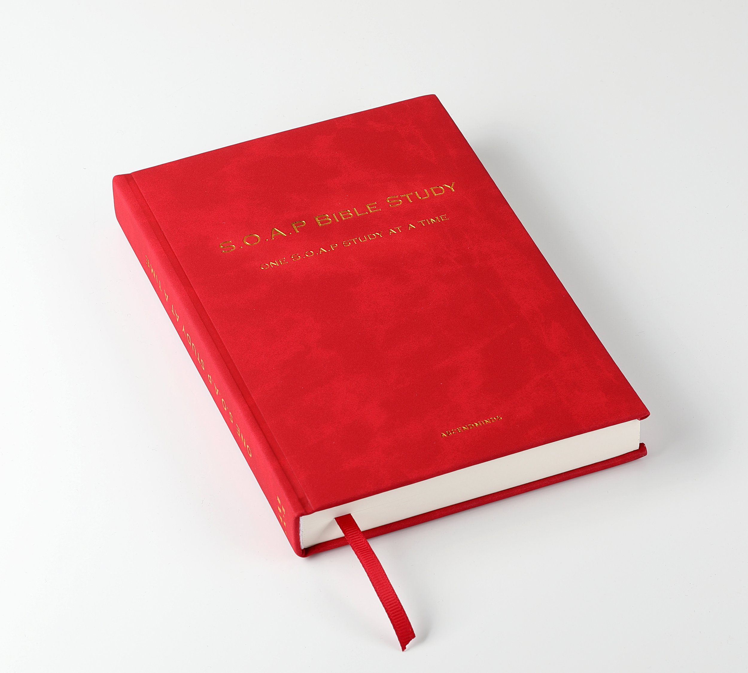 A red hardcover book titled 'S.O.A.P Bible Study' with gold lettering, a red ribbon bookmark, and a white pages edge, placed on a white surface.