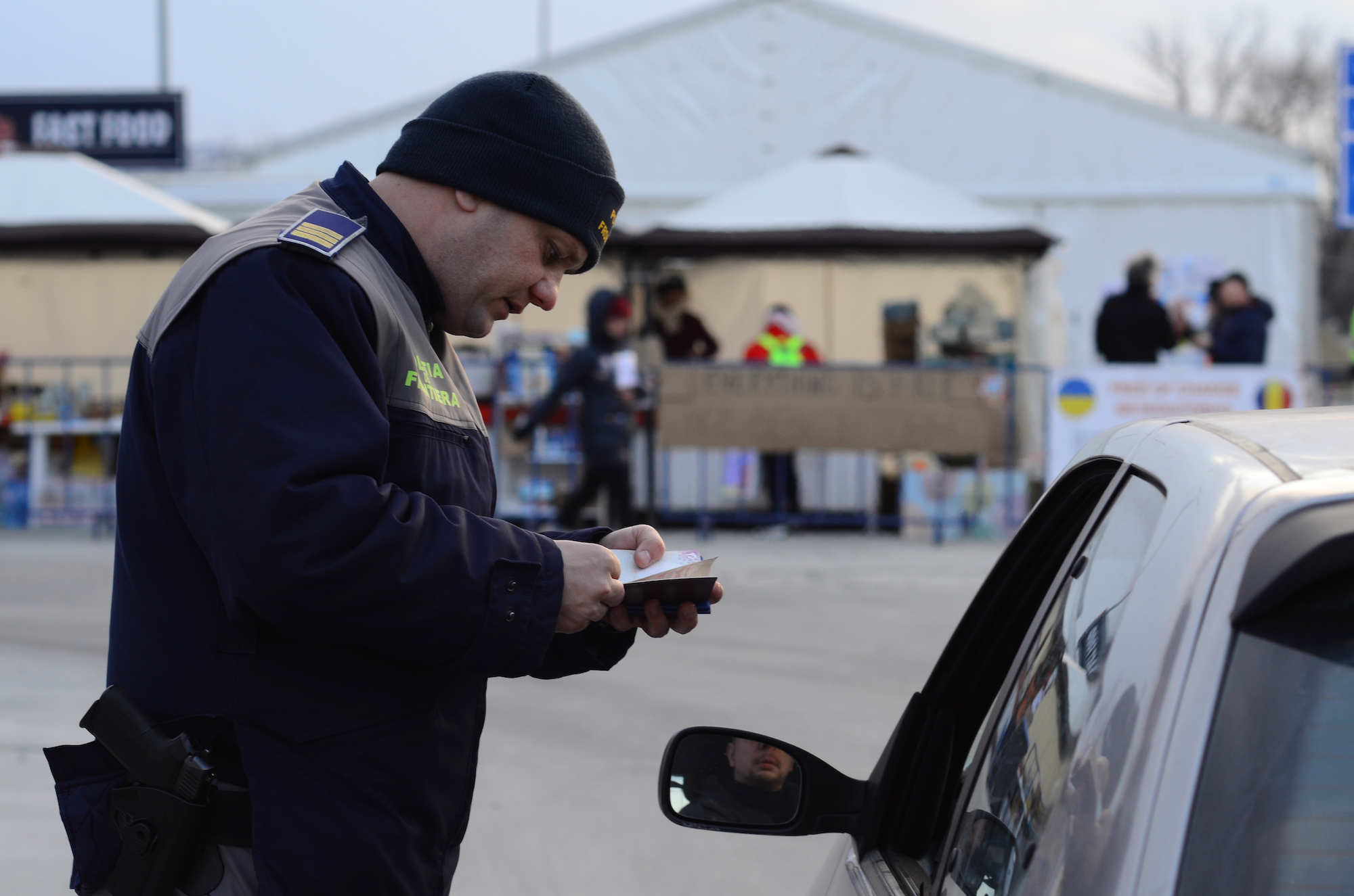 A Romanian border guard checks the documents of people driving from Ukraine