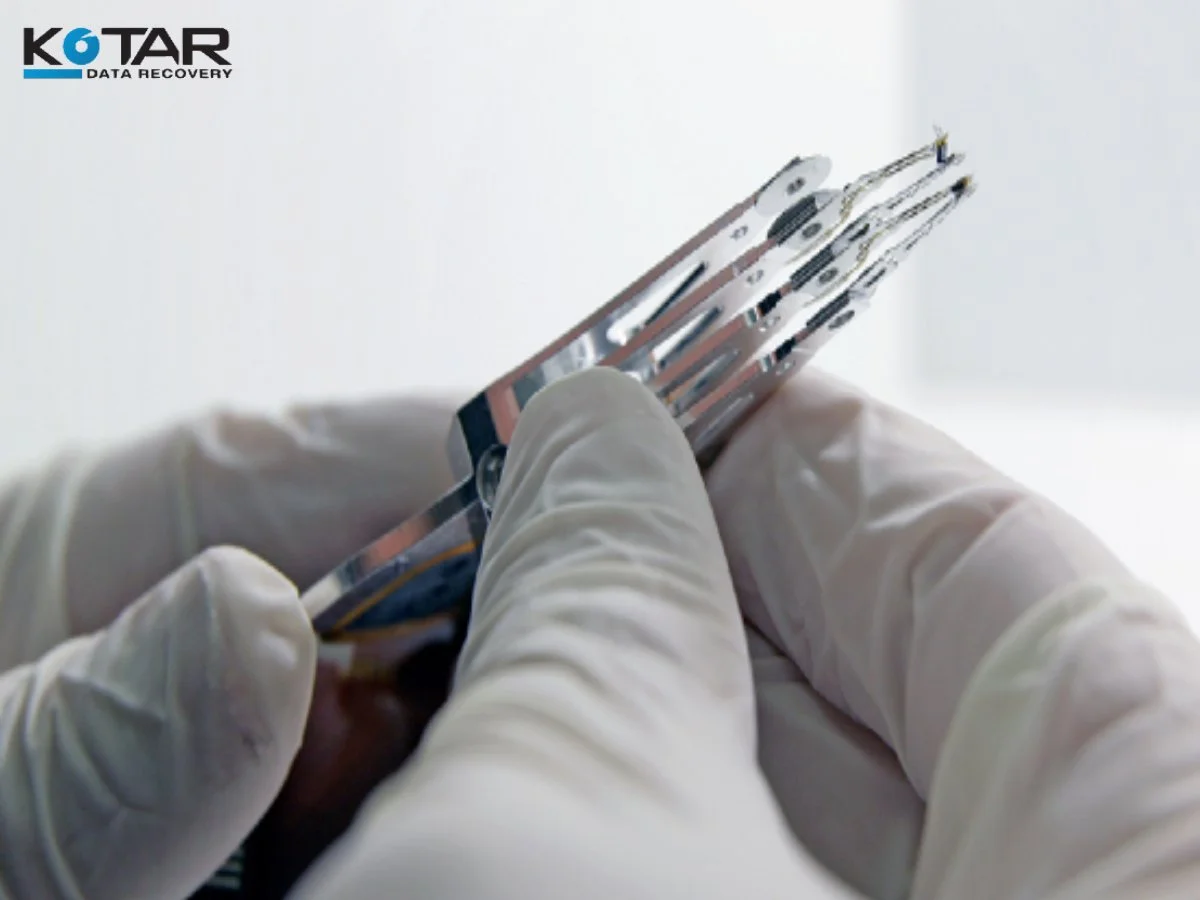 Gloved technician handling hard drive platters for data recovery.