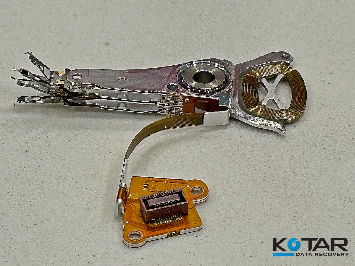 Disassembled hard drive actuator arm and read/write head assembly removed during professional data recovery process