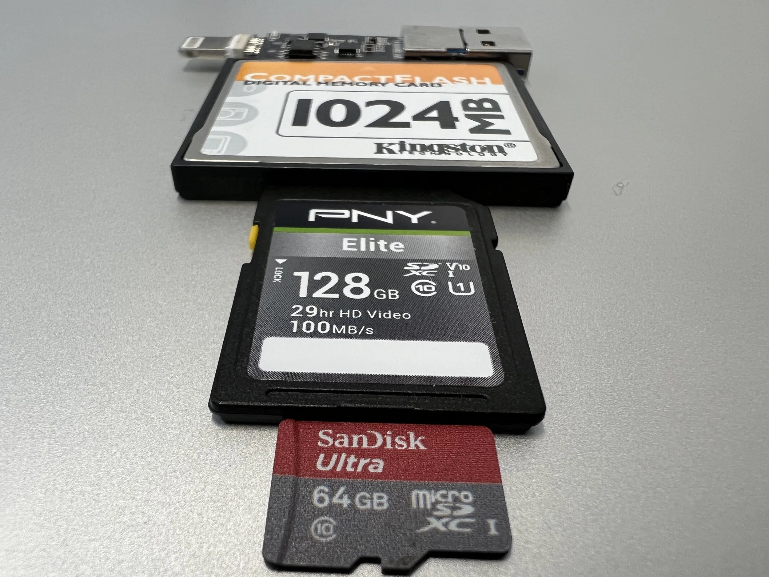 A computer microSD card, a 128GB SD card, and a 64GB microSD card laid on a flat surface.