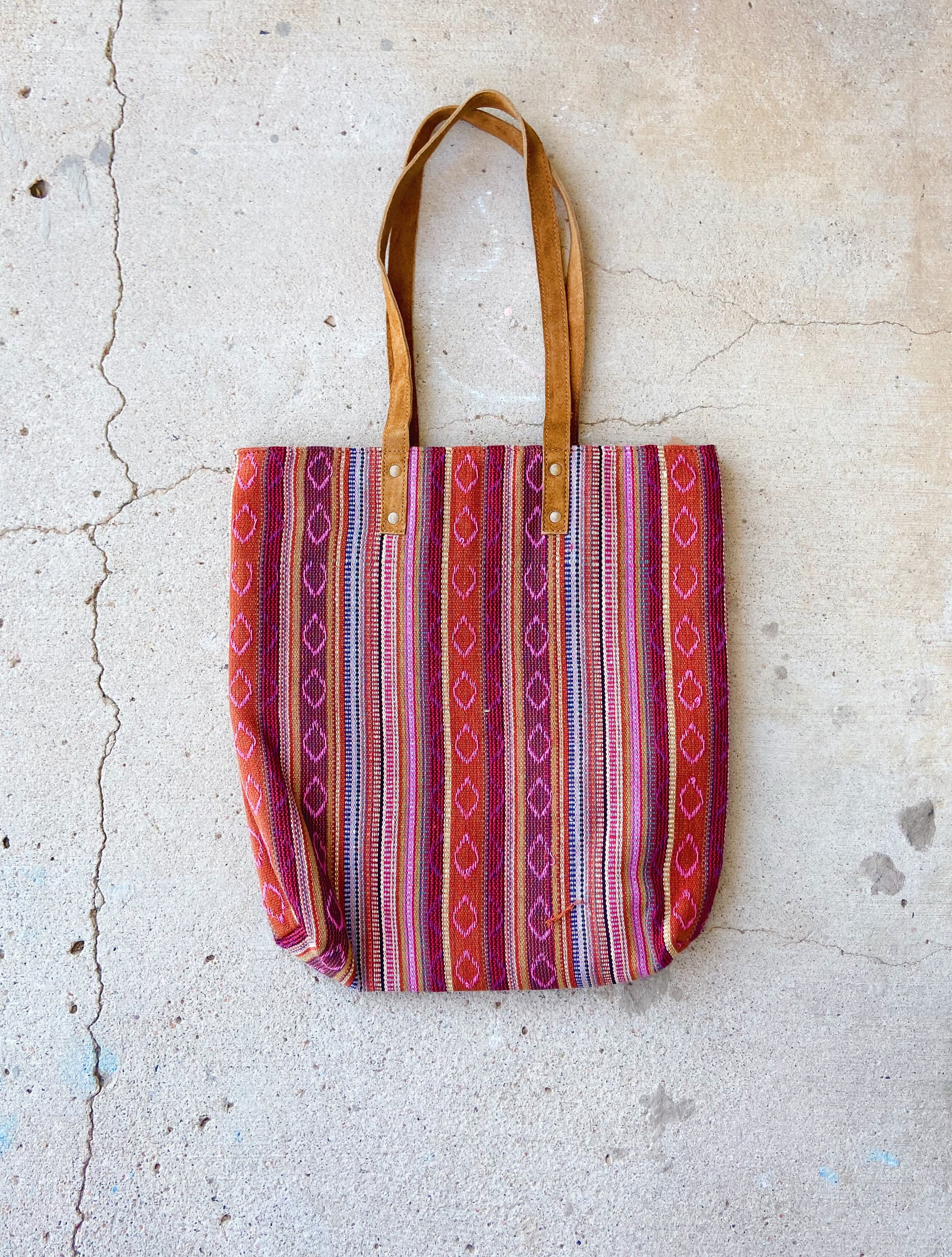 Desert Sunrise Tote Purse front view, showcasing the pink, red, blue, and white woven fabric and suede straps.