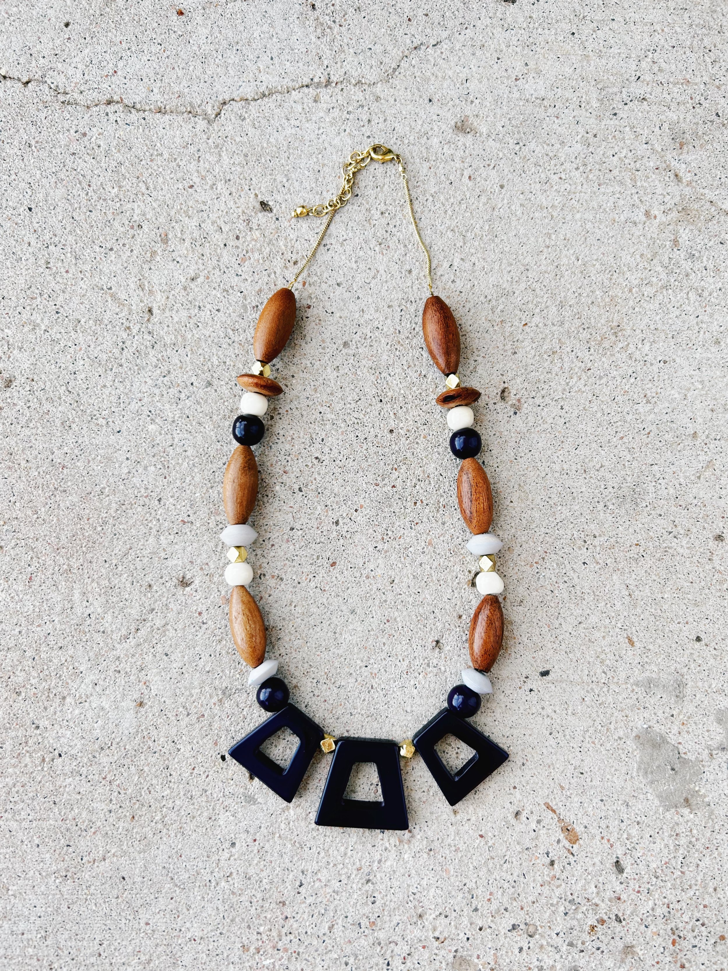 The Kolkata Necklace is made from up-cycled bone beads, recycled brass, navy blue resin, and wooden beads.