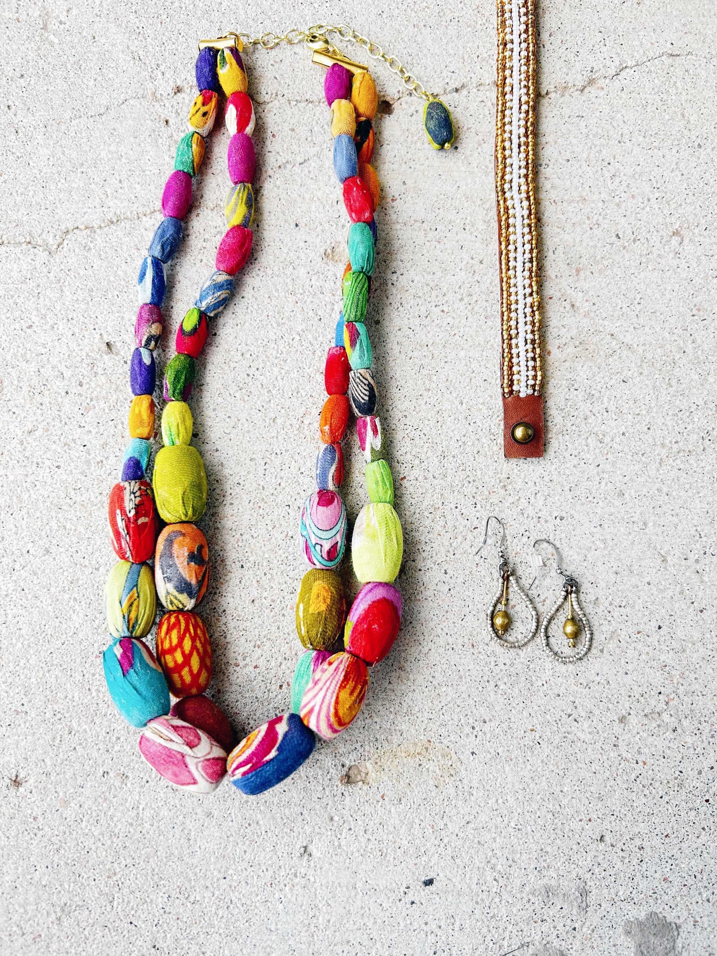 The Elliptical Layers Kantha Necklace is featured with the Mixed Metal Artillery Drop Earrings and Narrow Neutral Beaded Cuff Bracelet.