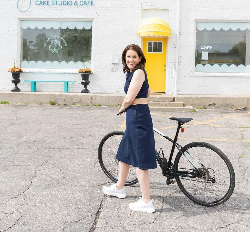 Dr Kim Bretz ND walking her bike in front of a bakery