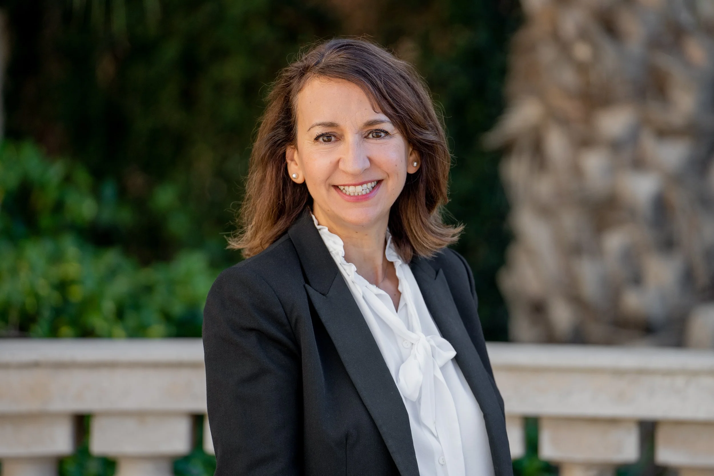 Woman in suit posing for her professional corporate headshot in outdoor setting