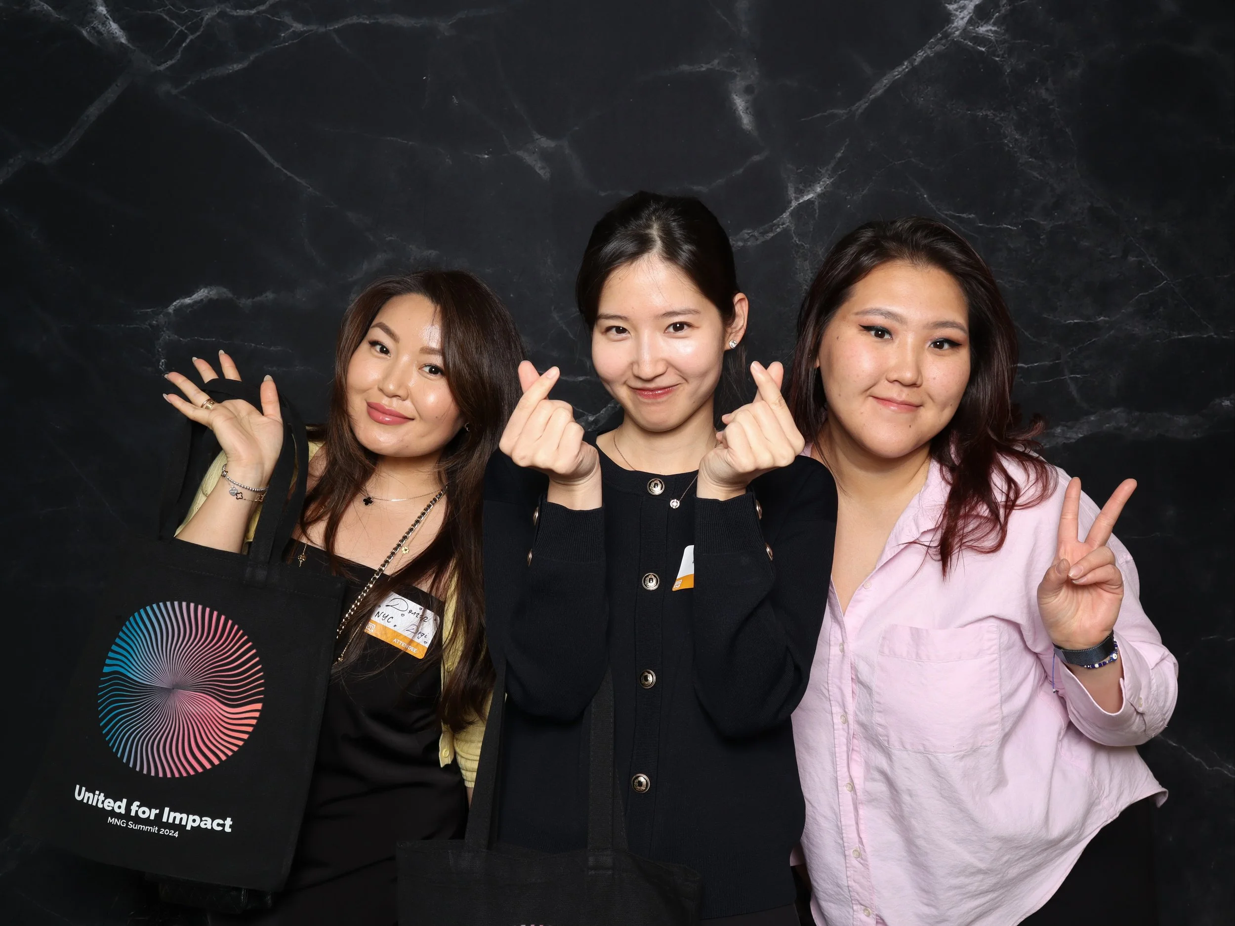 Three women posing together at a photo booth event