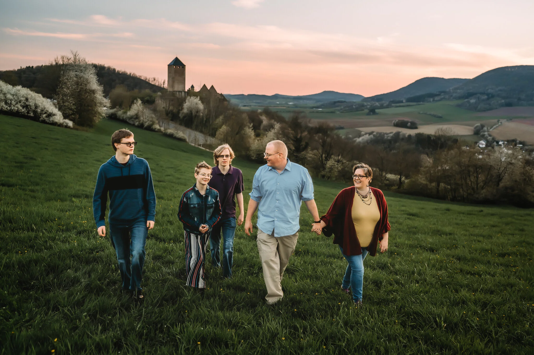 Family of five walking with castle in background at sunset