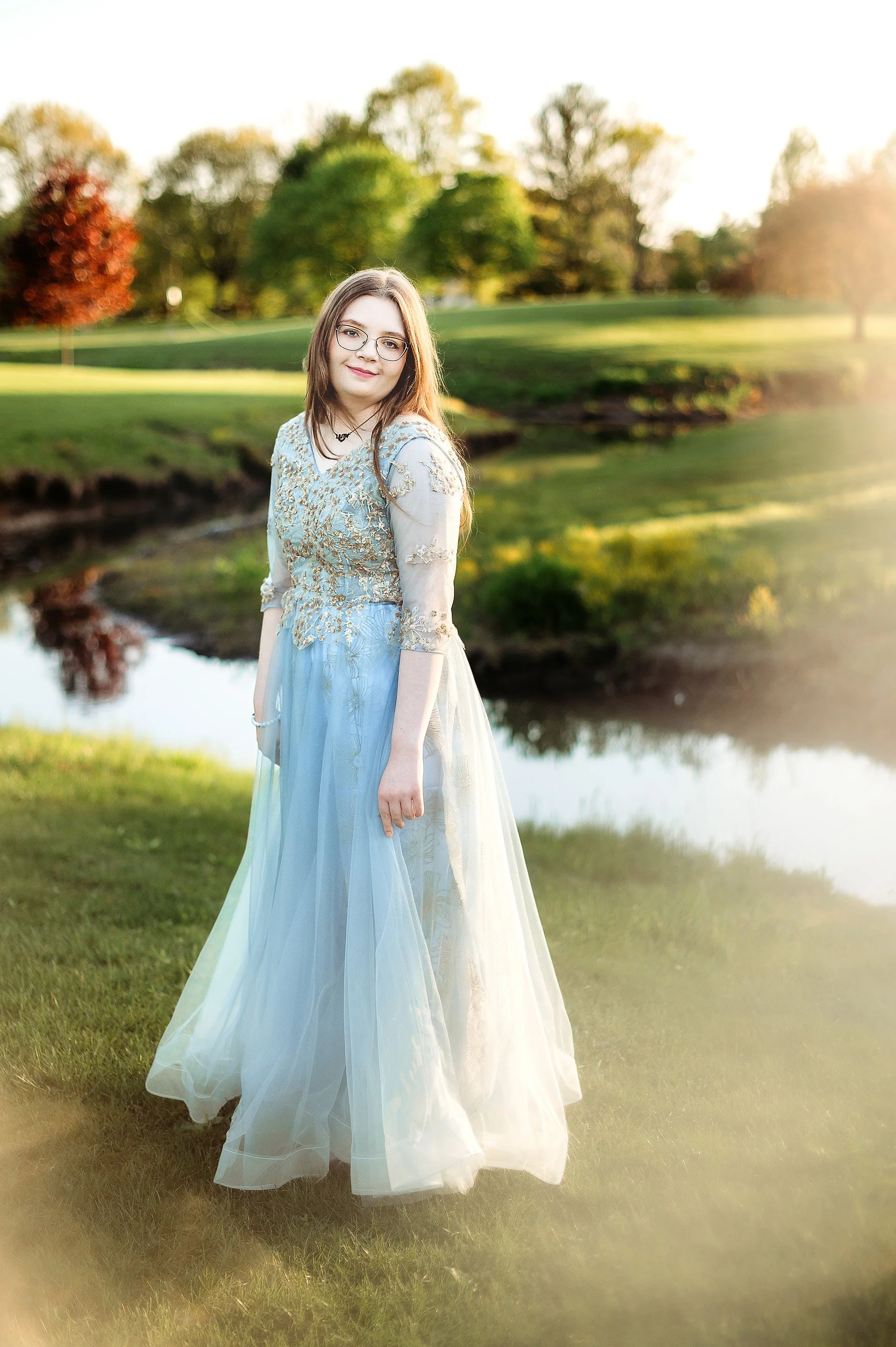 Senior girl wearing prom dress in front of meandering stream