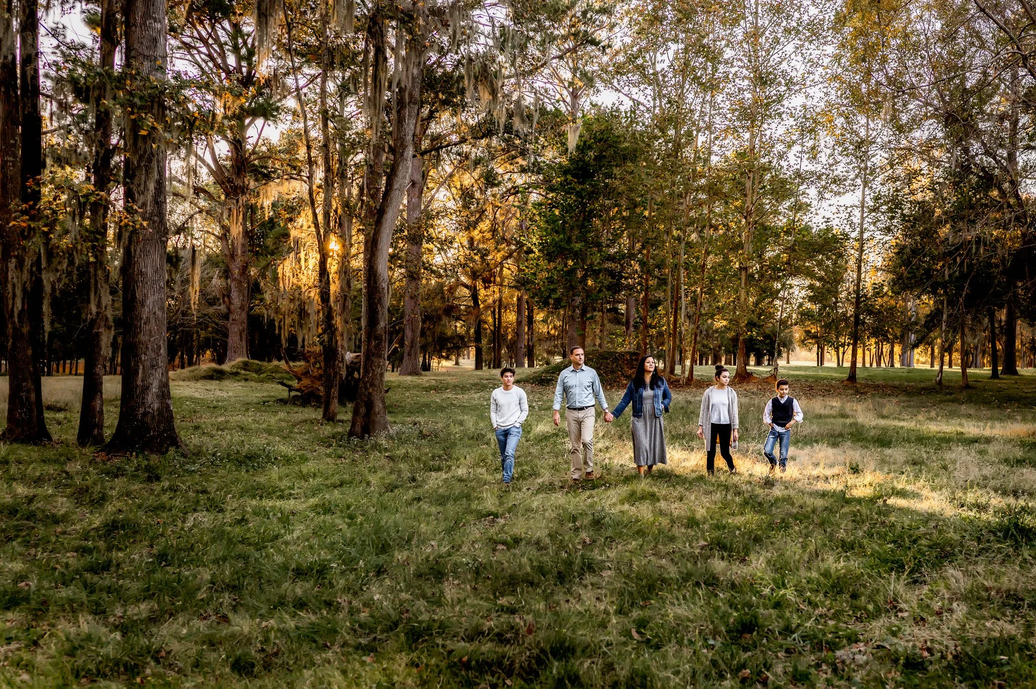Champaign Illinois Family Photographer. Family consisting of parents and teens walking in picturesque wood area.