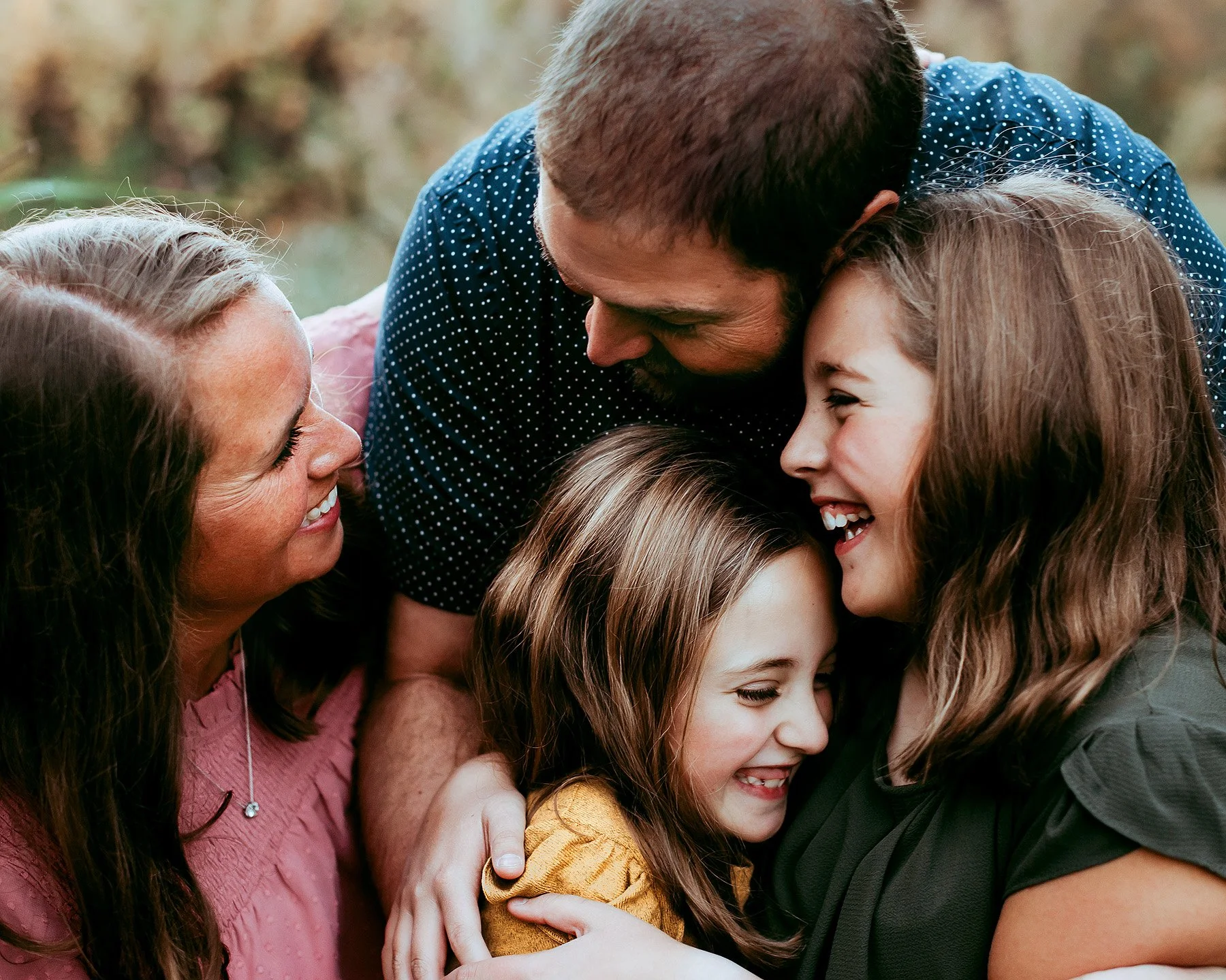 family of four hugging in candid professional photo