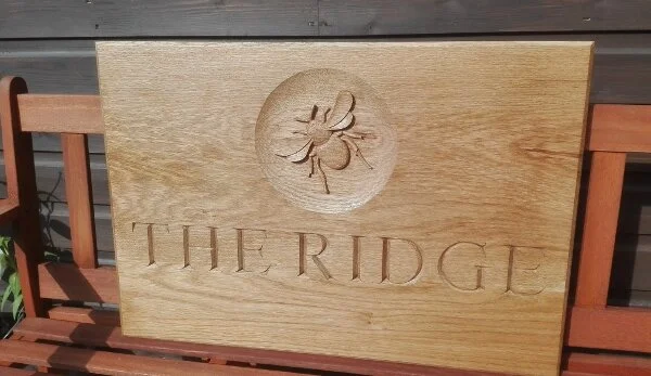 Hand carved house sign in oak incorporating a bee motif