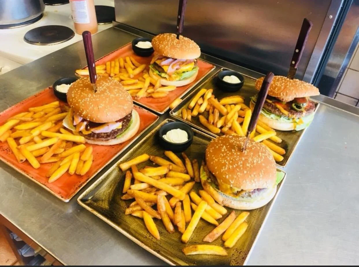 Neljä burgeriannosta ranskalaisilla perunoilla. Veitset on laitettu tukemaan burgeria ja helpottamaan syömistä.
