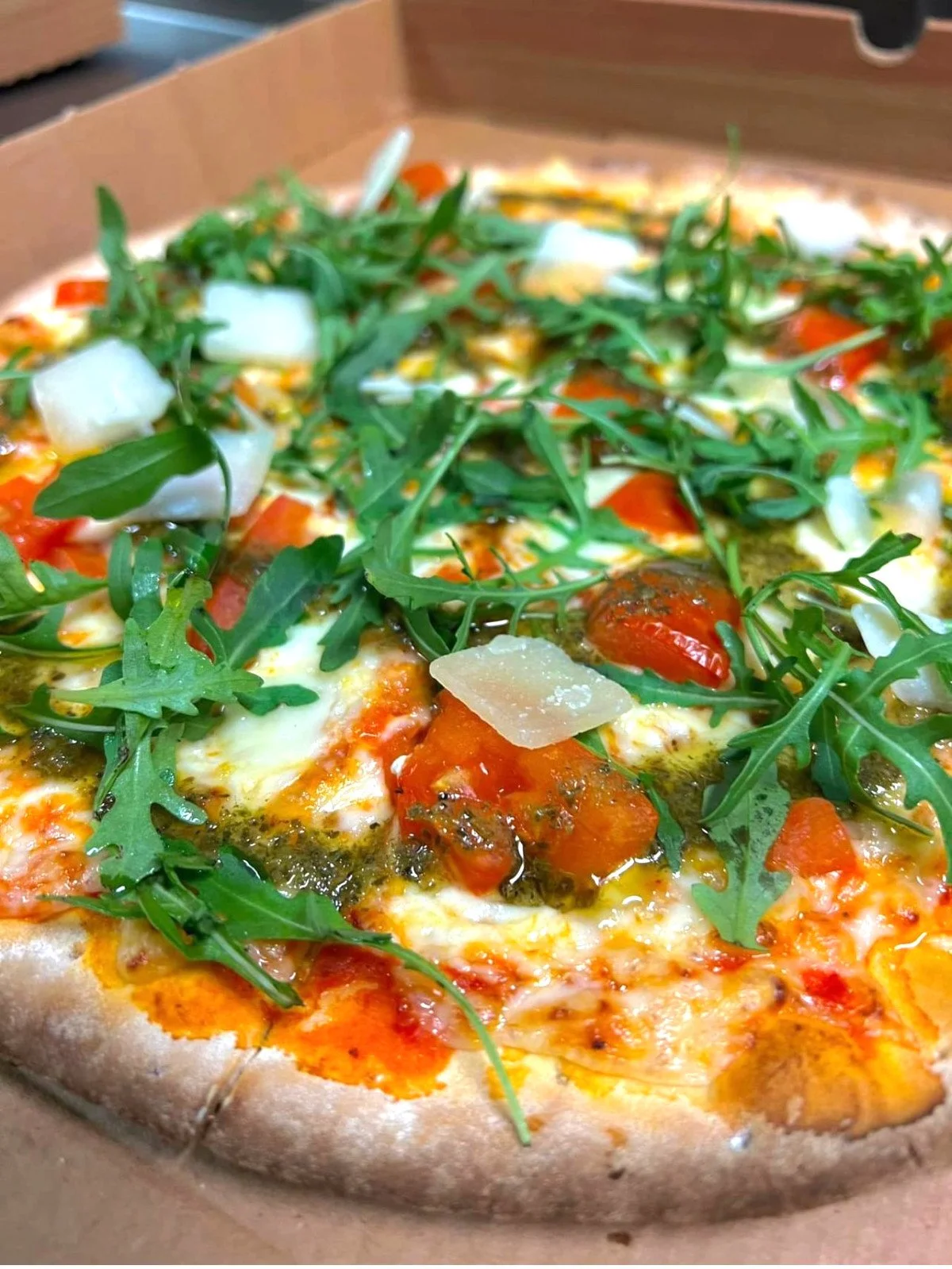 Pizza parmesanilla, rucolalla ja tomaatilla.