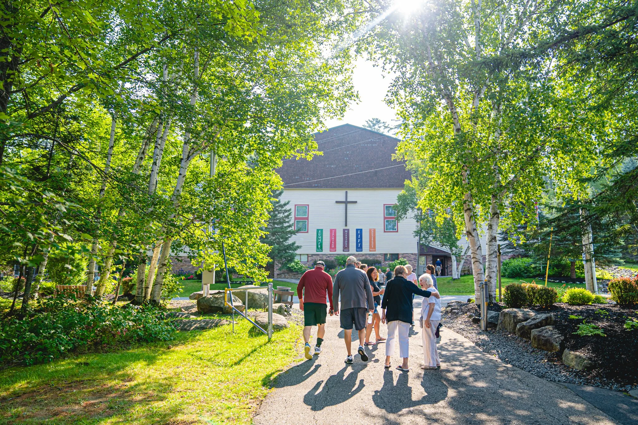 Families walking towards the Chapel building at CAMP-of-the-WOODS.