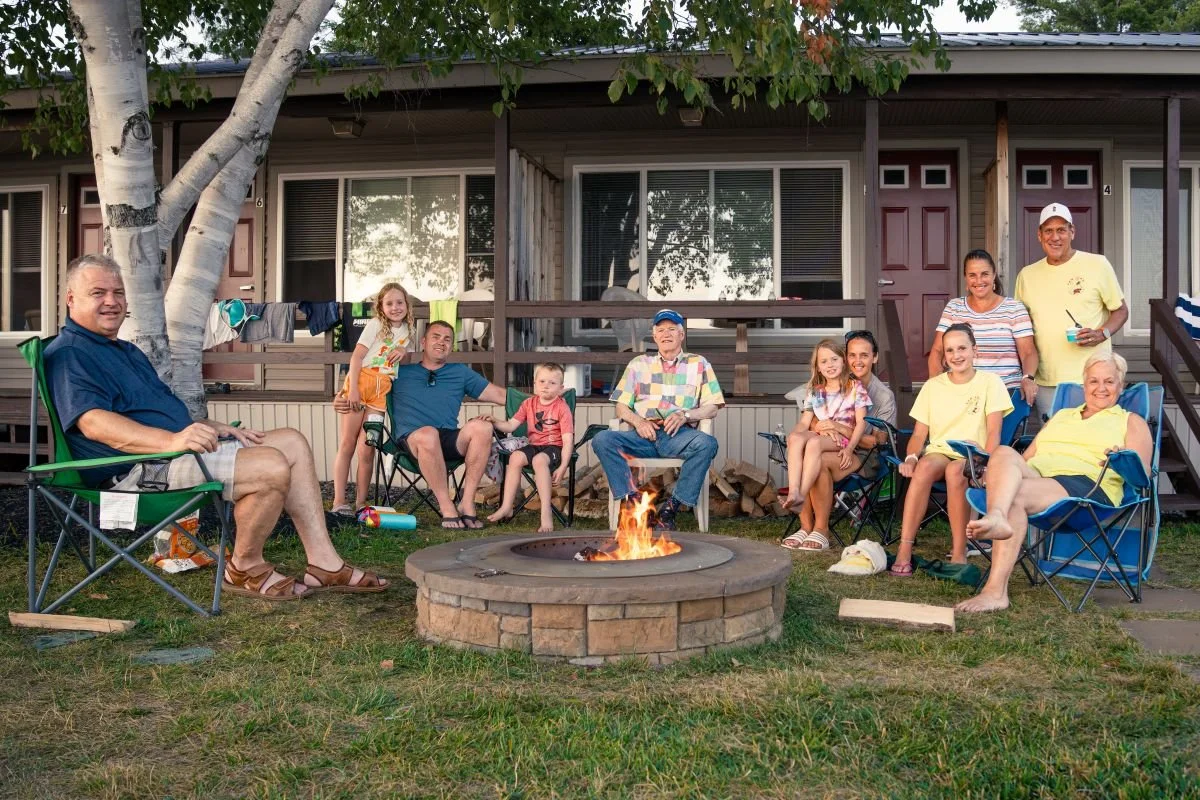 Family at CAMP-of-the-WOODS sitting around a fire.