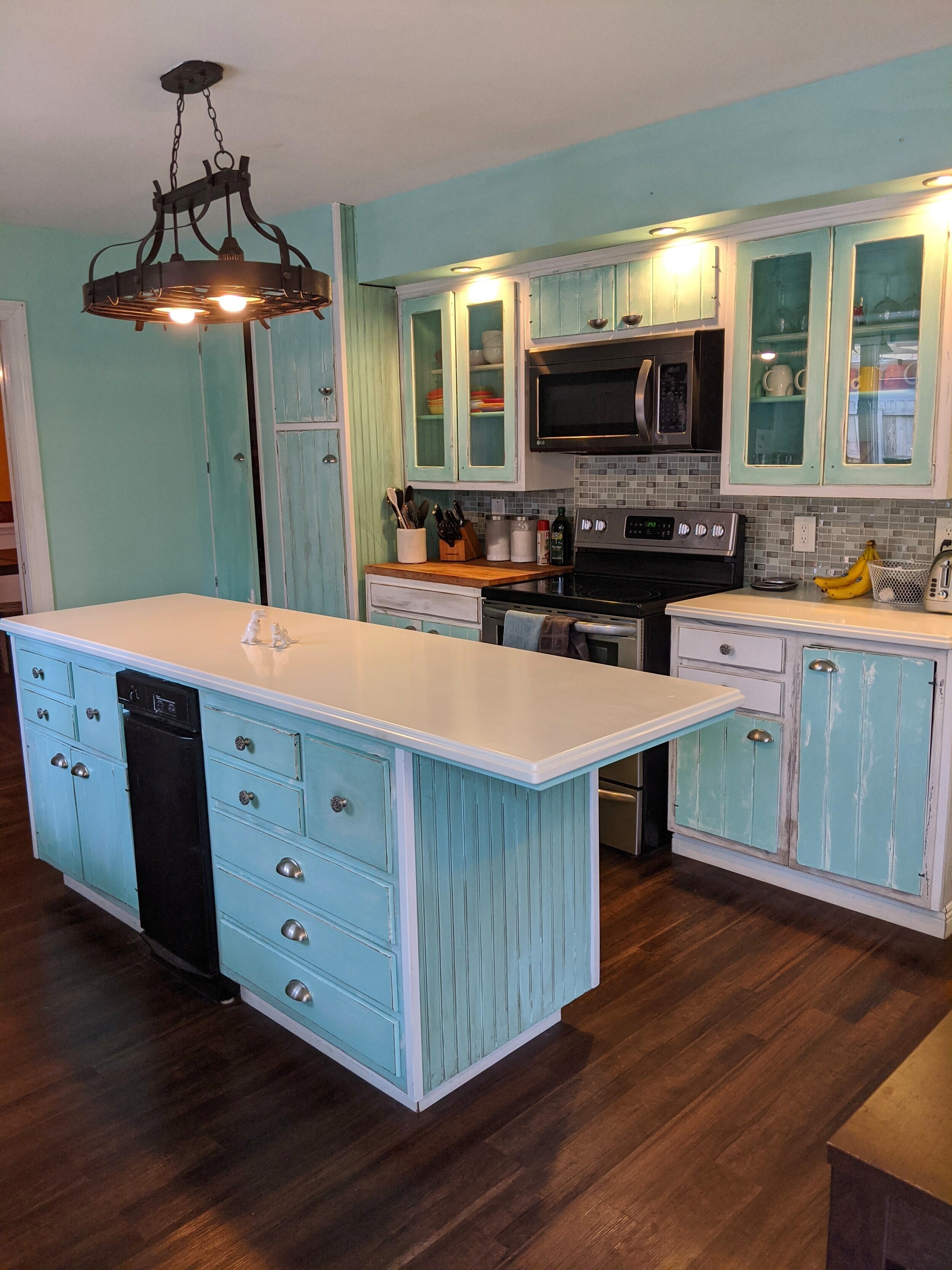 a bright kitchen with teal cabinets, mismatching tile backsplash