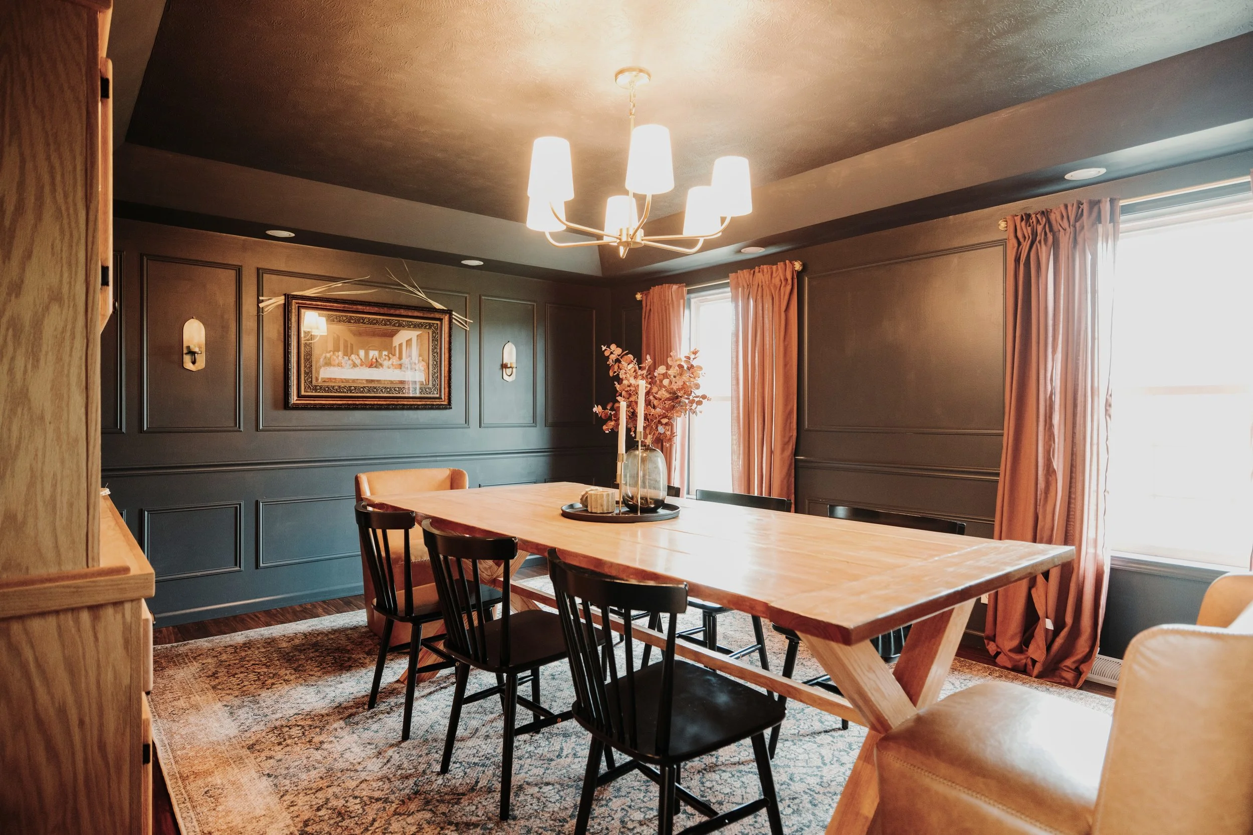 Dining table with black Windsor chairs and framed art