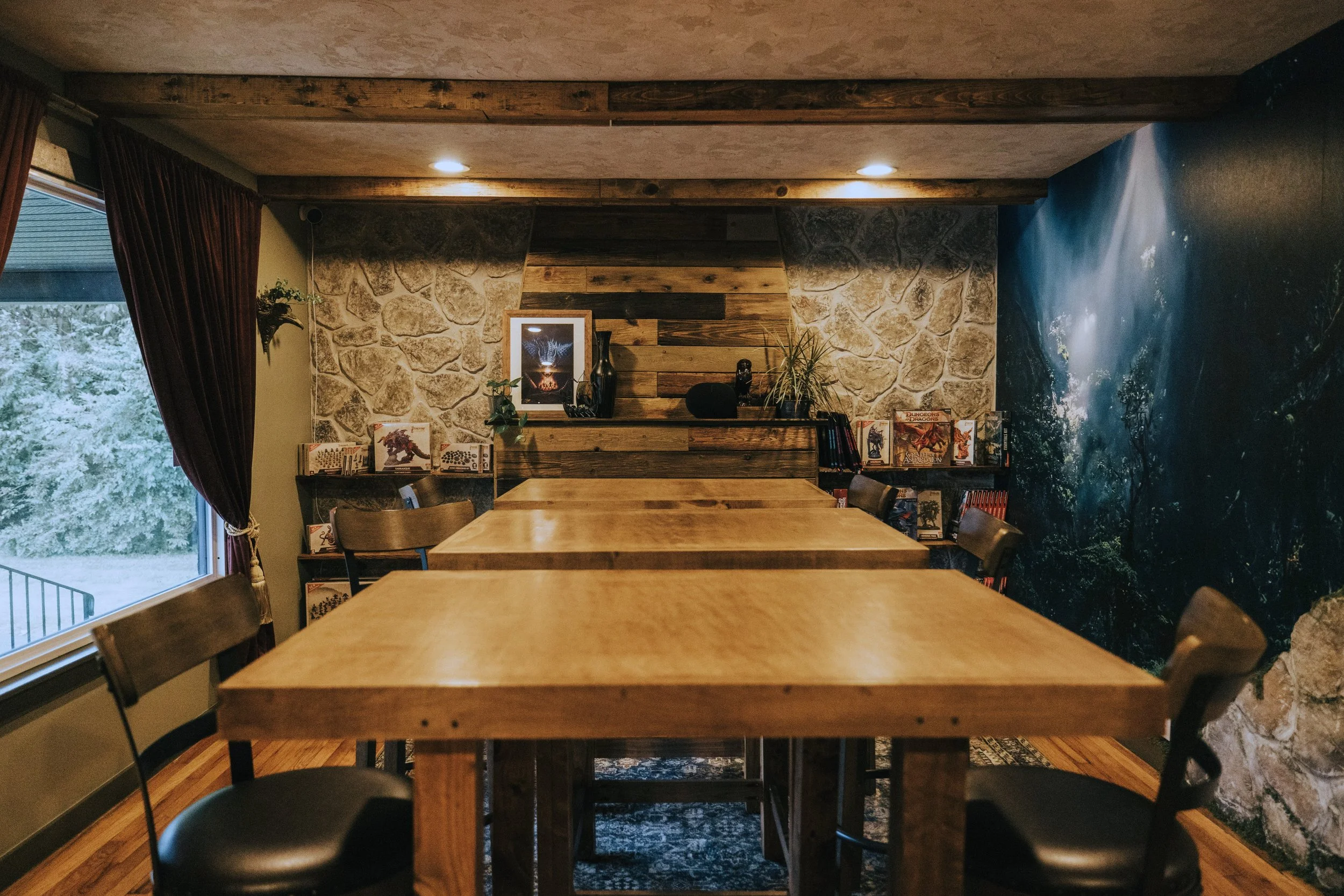 Wood gaming tables in front of a fantasy mural and stone accent wall