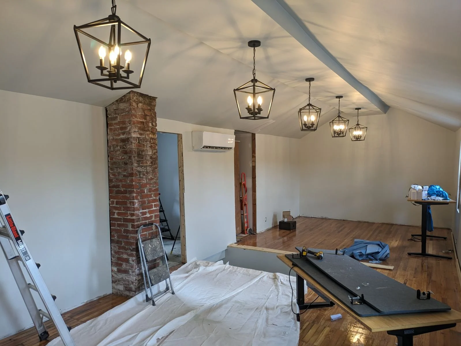 Lofted room with hanging lantern pendants and brick chimney