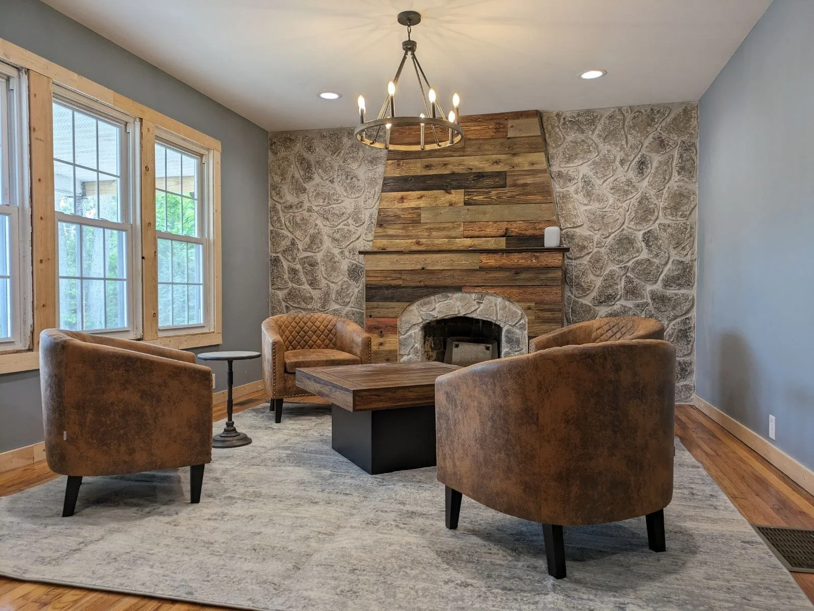 Leather chairs around table in front of fireplace and stone wall