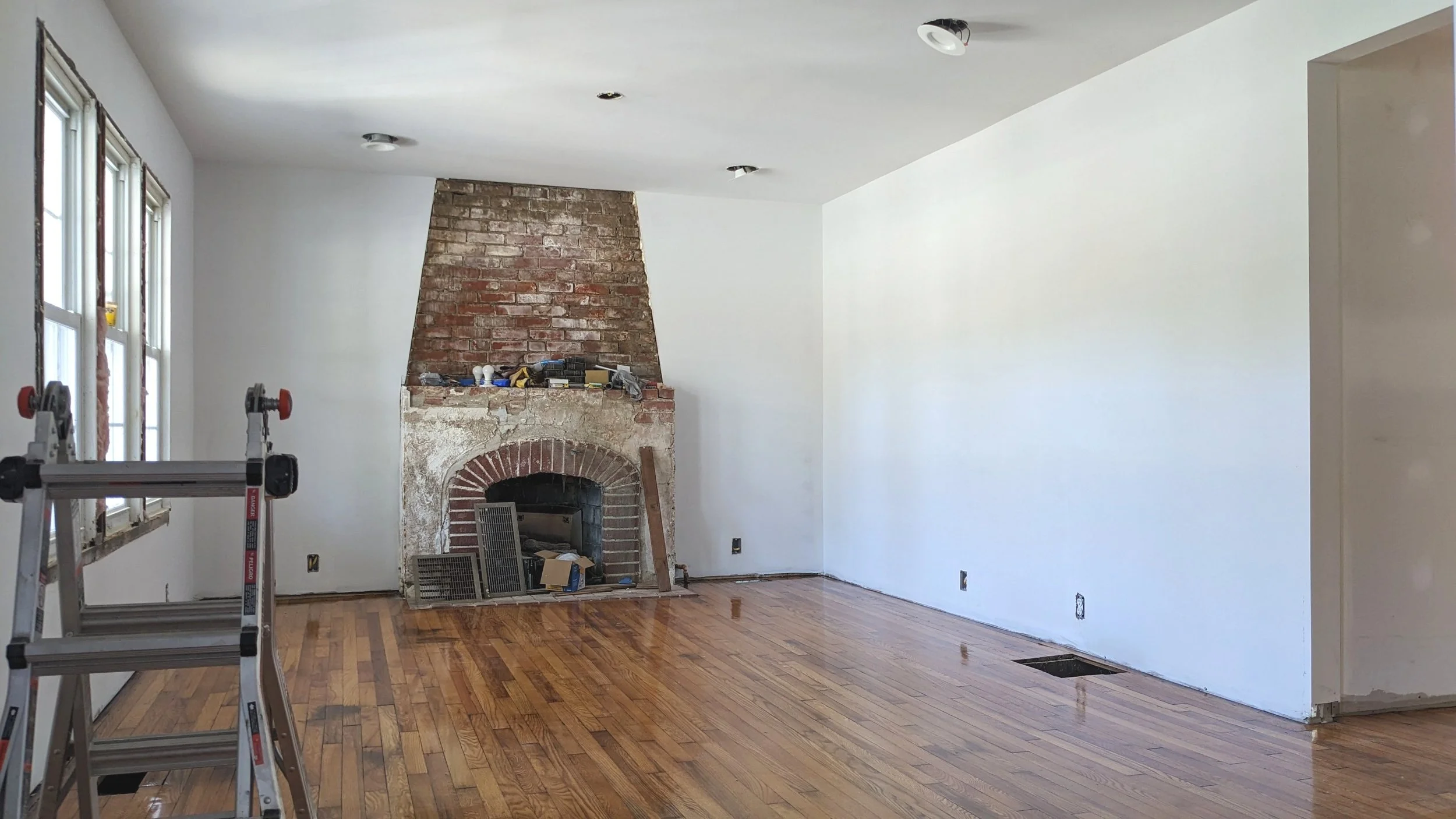 Empty room with brick fireplace wood floors