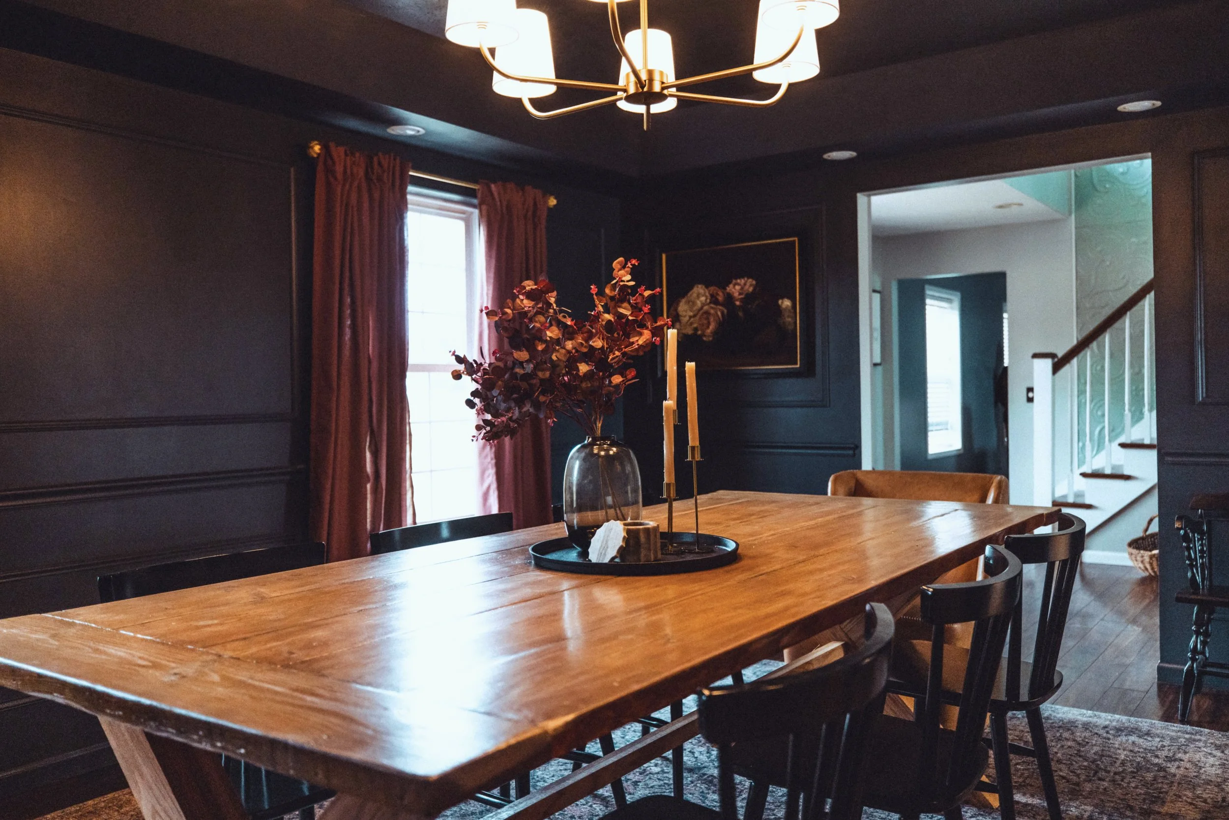 Moody dining room with framed floral art and brass chandelier