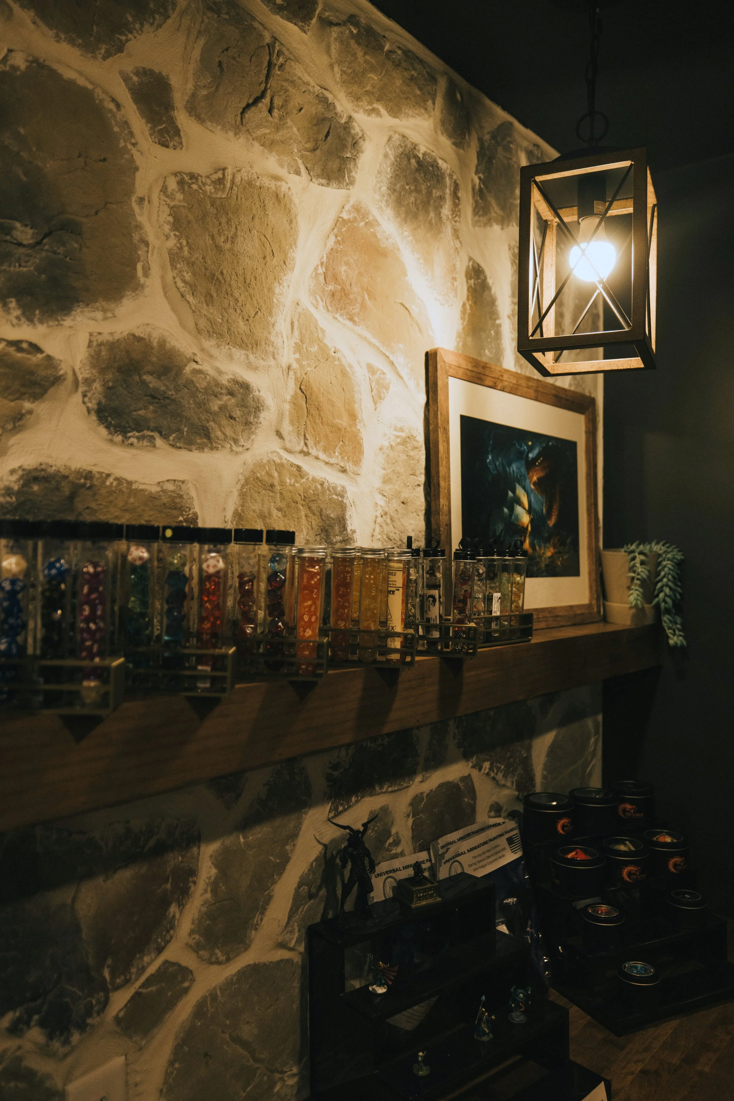 Glass dice vials displayed on wood shelf against stone accent wall