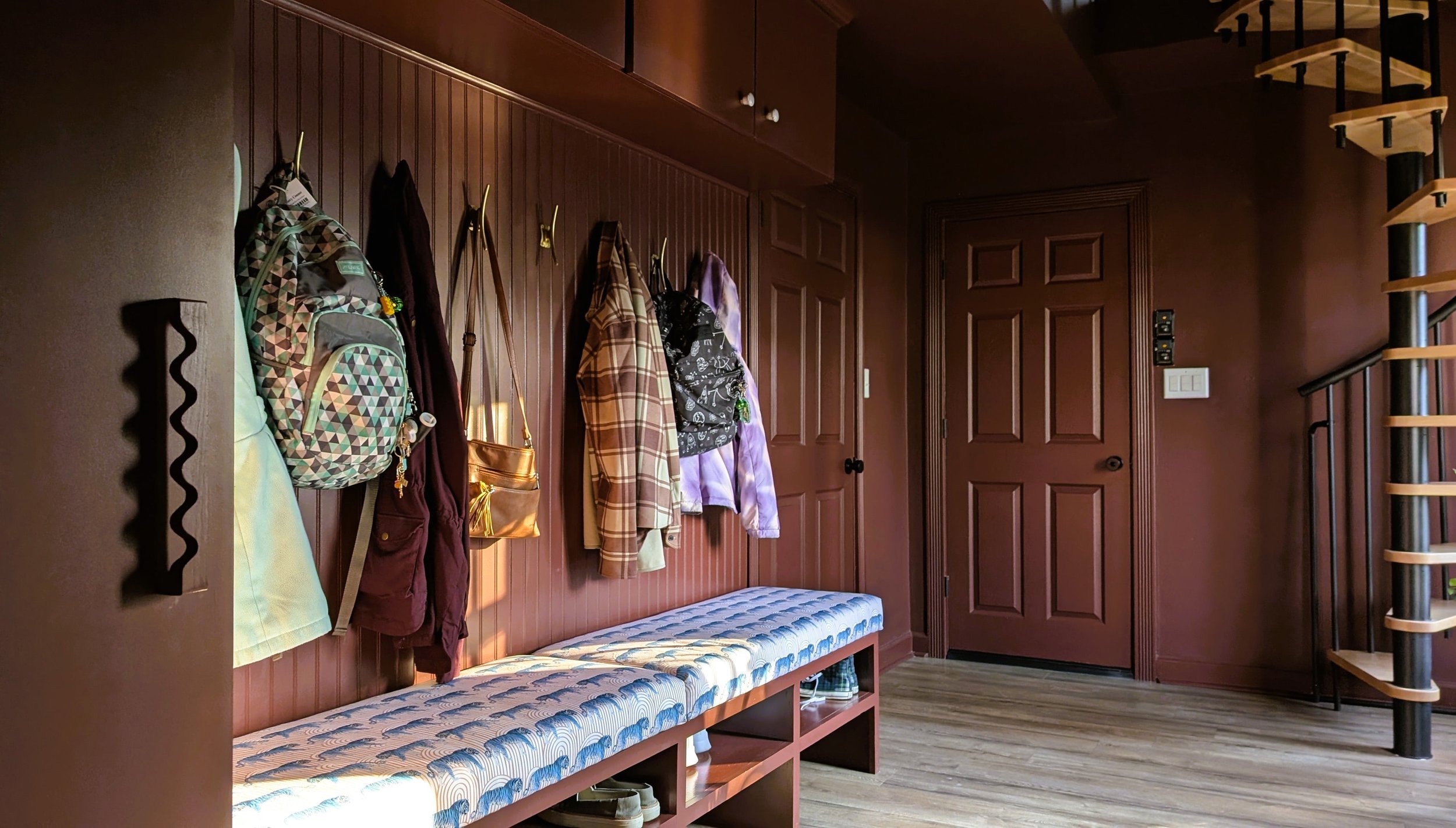 Mudroom storage wall with spiral staircase in background