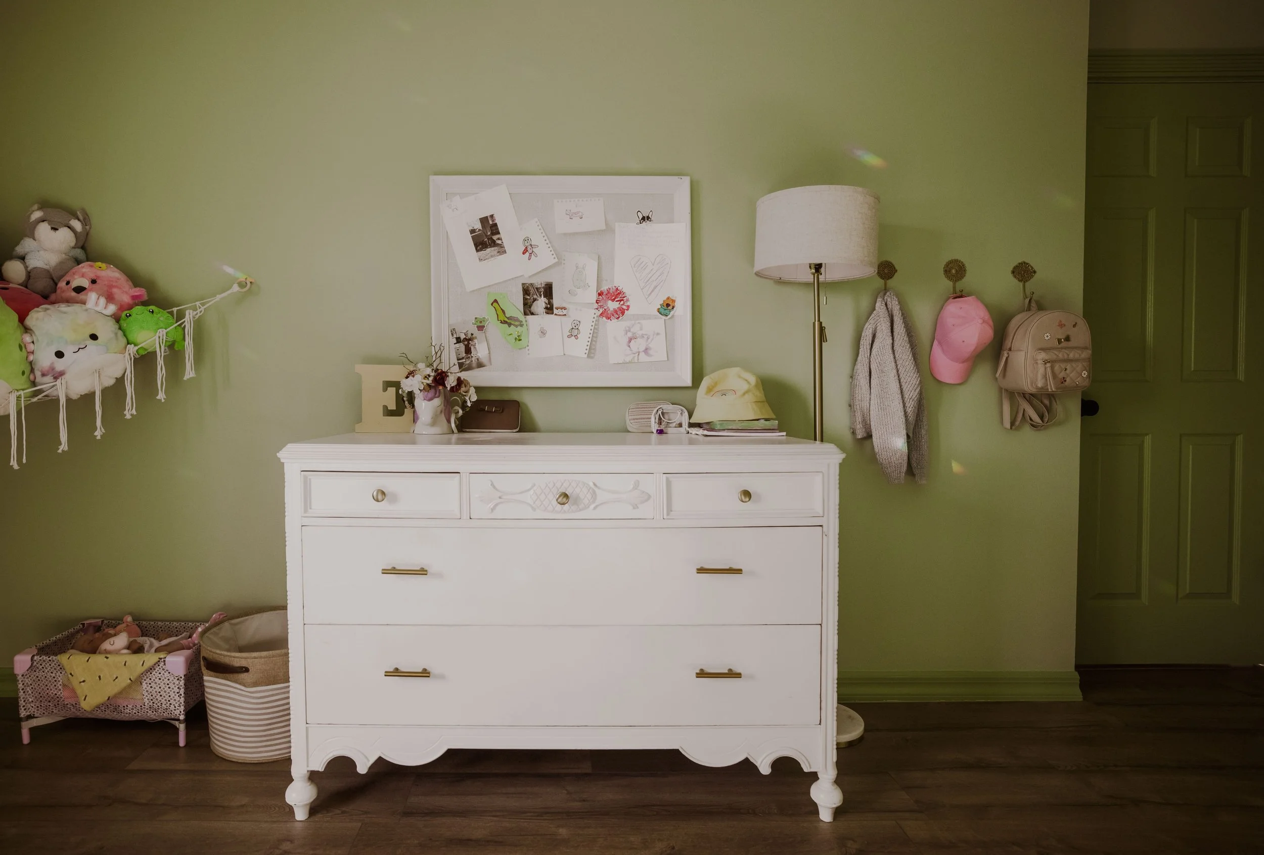 White dresser and corkboard in green tween bedroom