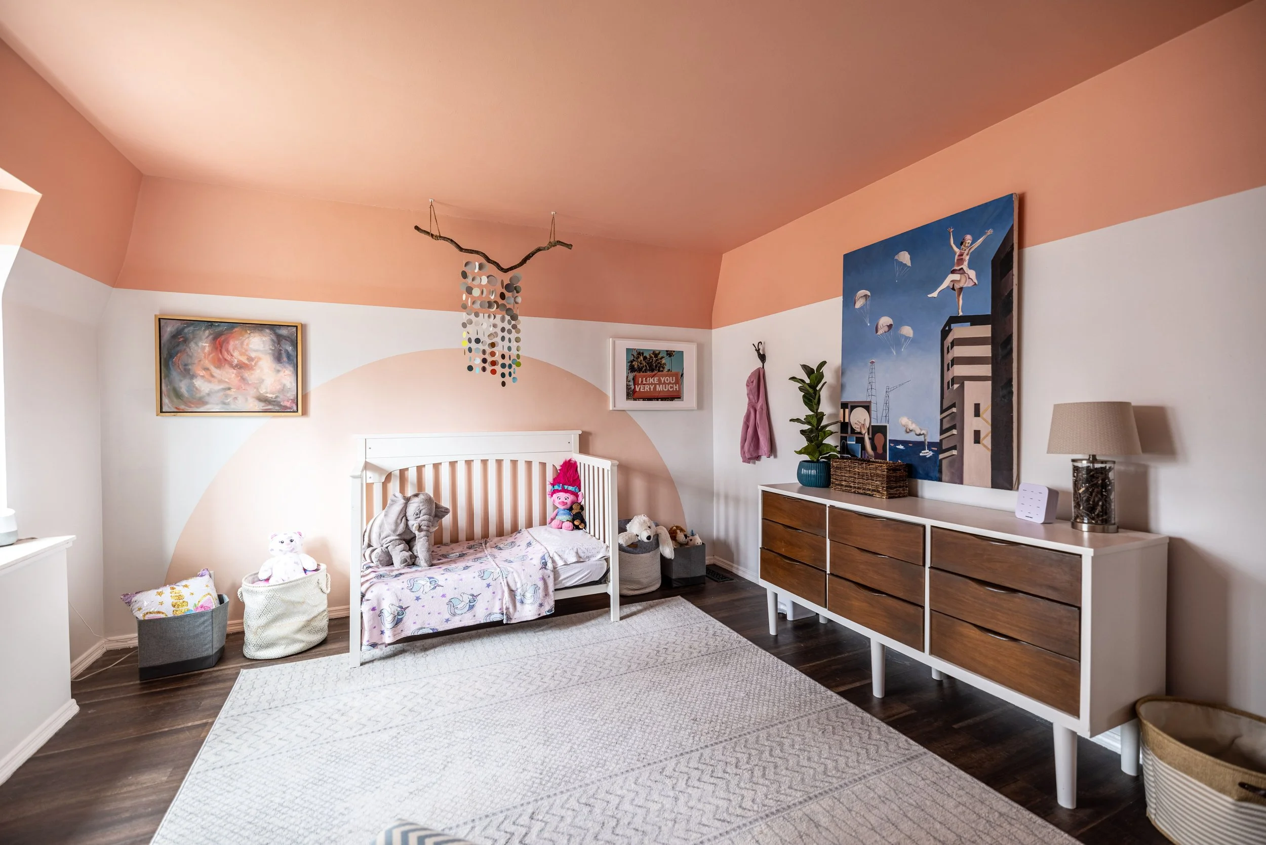 boho pink nursery with mid century dresser and mobile