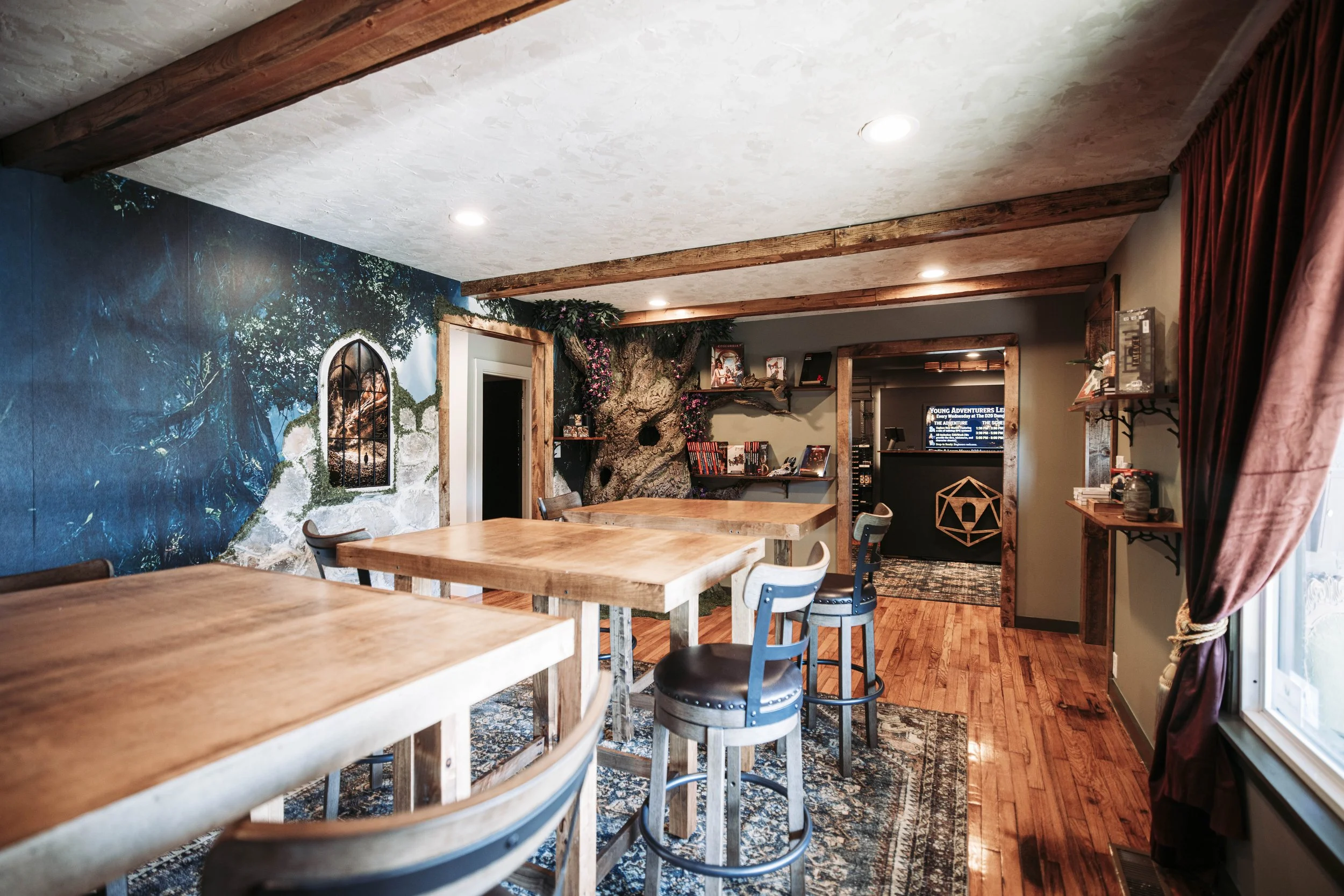 Full view of fantasy-themed gaming hall with mural, tree, and tables