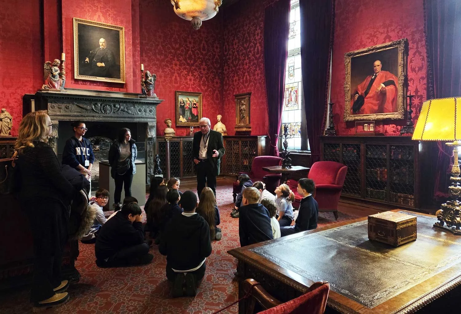 Morgan Library, Pierpont Morgan study in red damask with group of kids listening to guide.