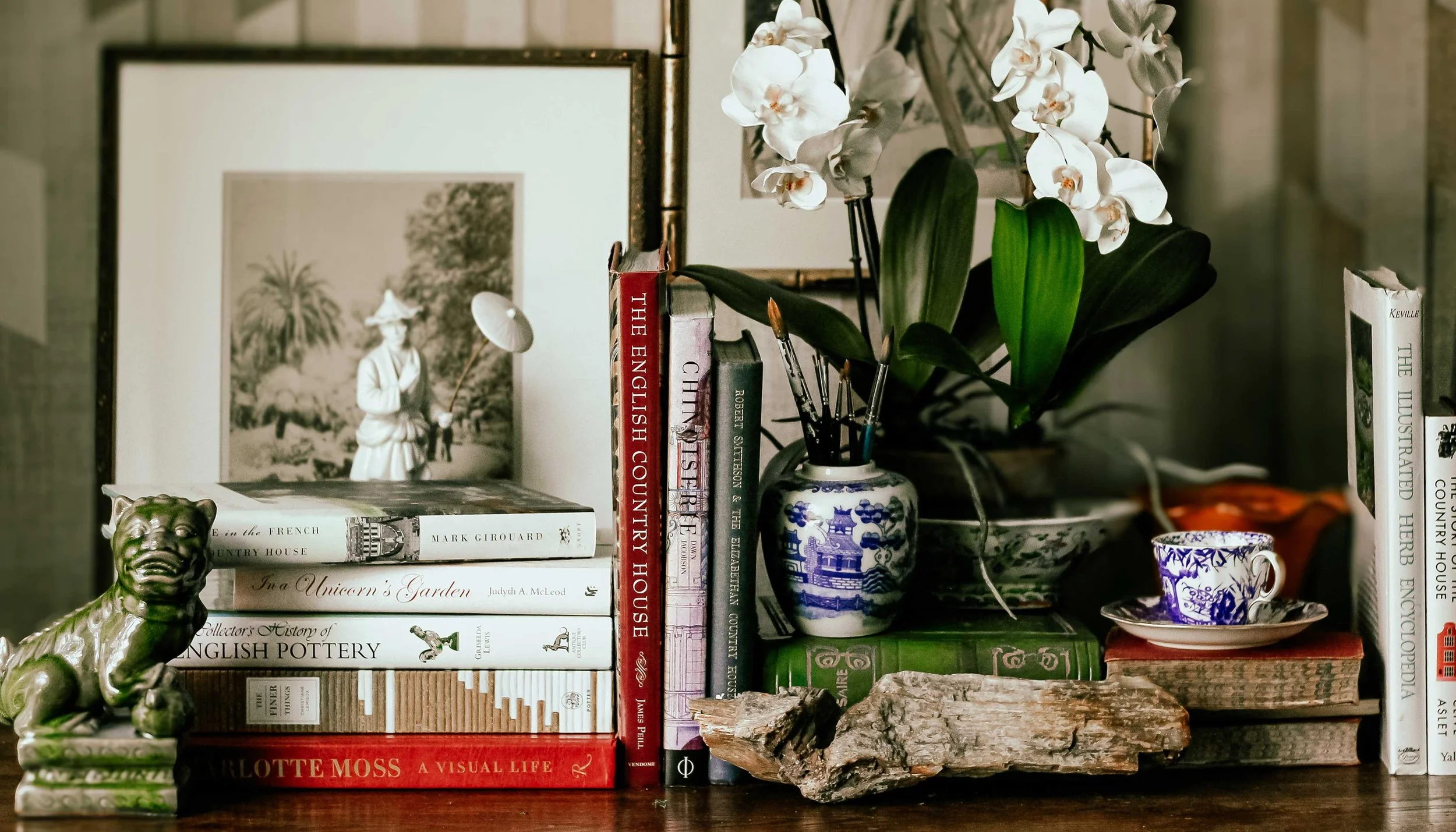 Table top with design books and porcelain pieces.