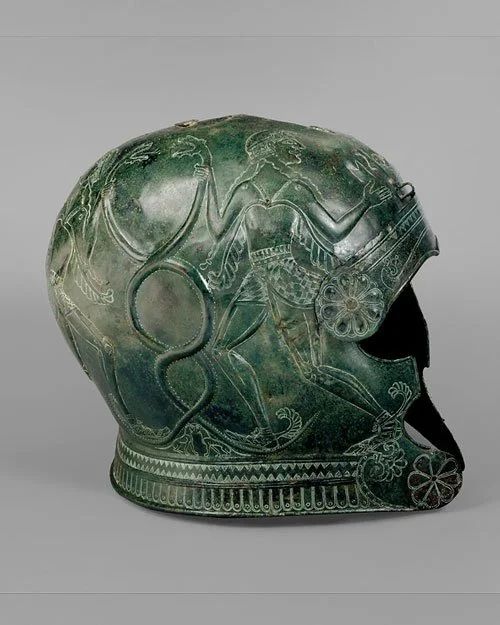 Bronze helmet from southern Crete in Greece. The design, on both sides, shows a young man holding taking hold of two intertwined snakes. 7th c BCE. Met Museum