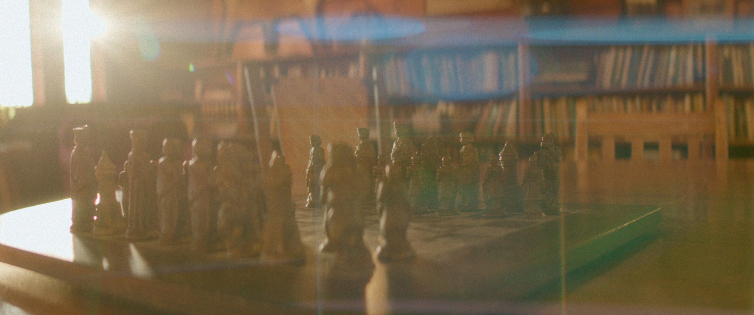 A chess board with morning sun flaring in the lens.