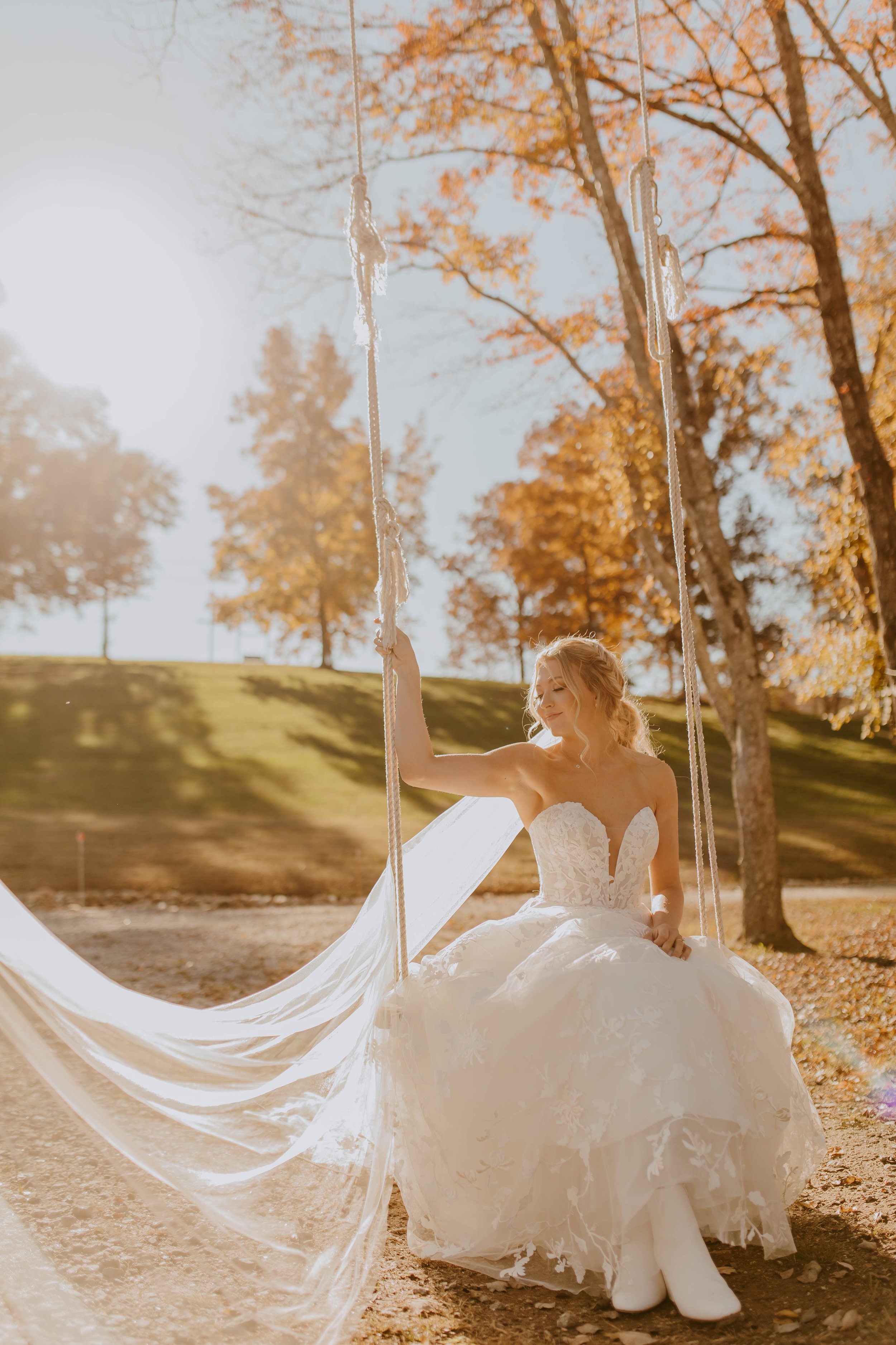 Bride on swing with beautiful fall leaves in the background.