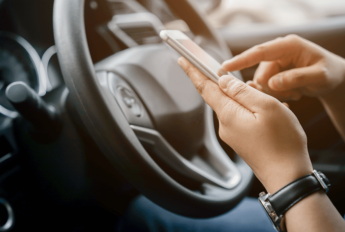 Person using their phone while sitting in the driver seat