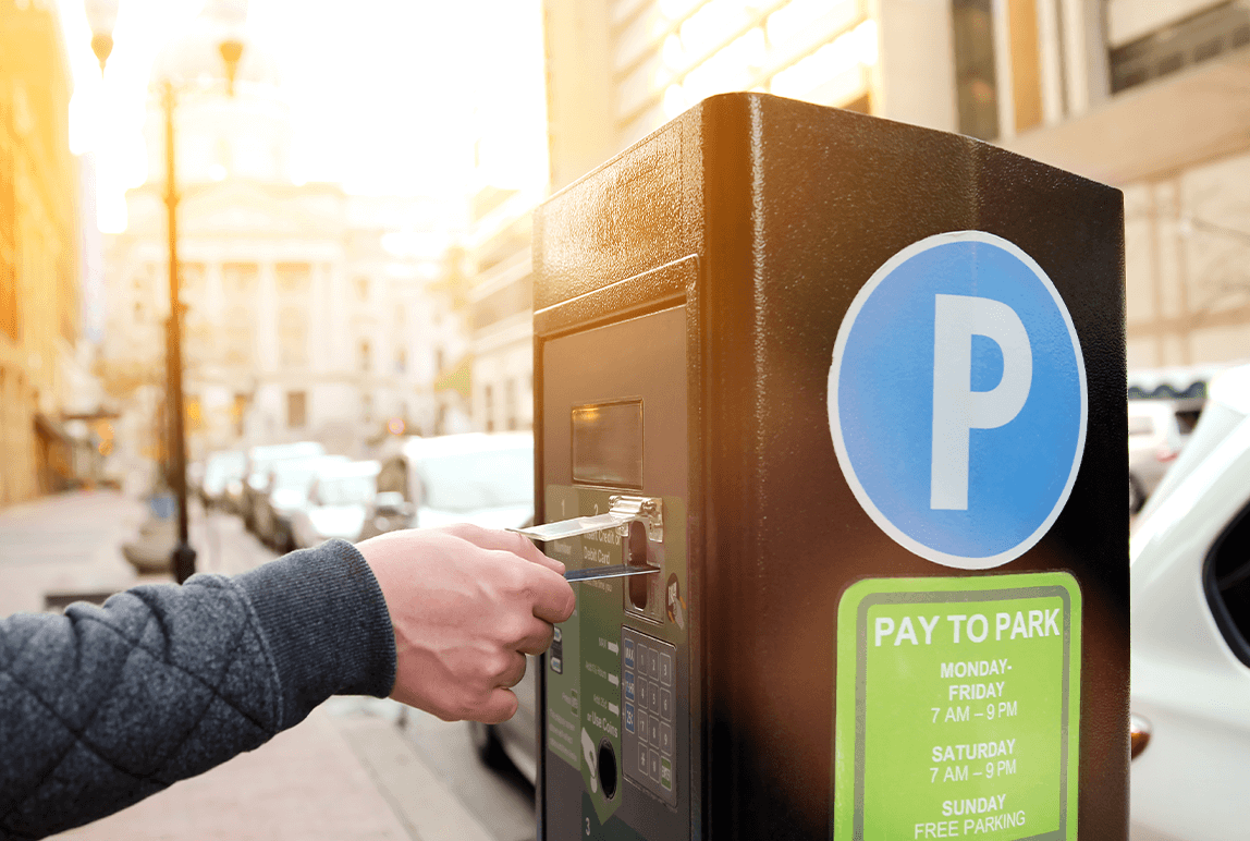 Someone paying for parking at a parking meter using a credit card
