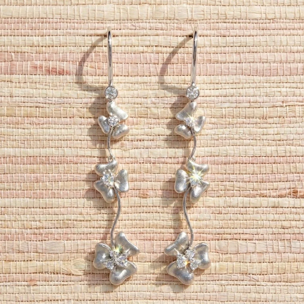 Perfect for the bride who wants something timeless, feminine, and quietly unforgettable. ⁠
⁠
These triple flowerhead drop earrings feature three matte white gold blooms, gracefully graduating in size from top to bottom. Every detail is thoughtfully c