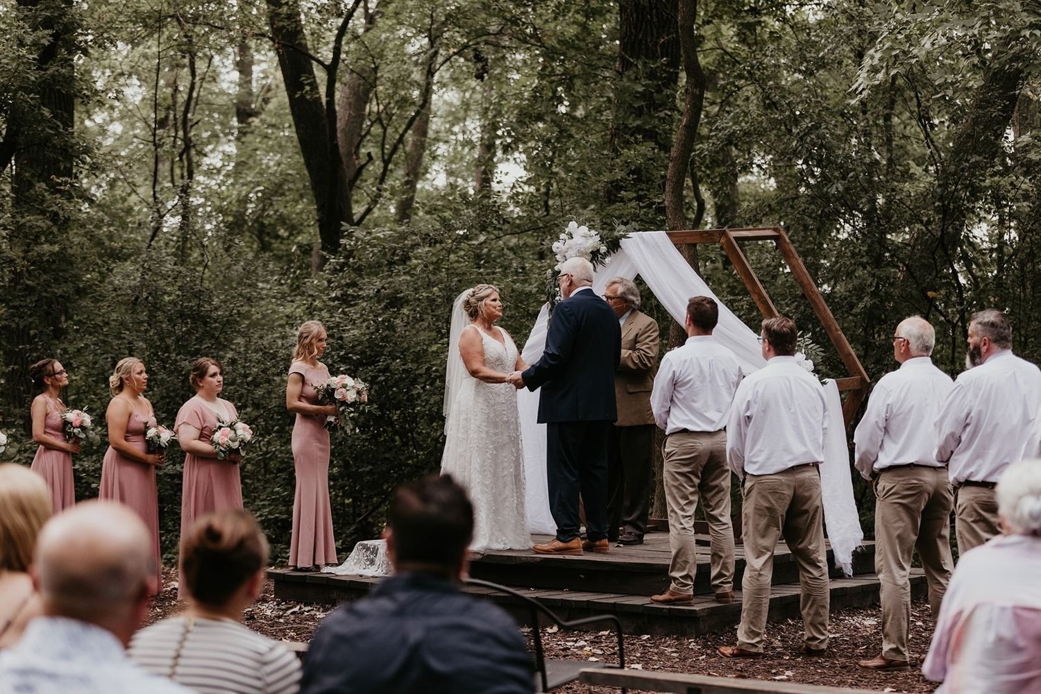 Long reception tables styled with greenery and lanterns beneath the barn’s wooden beams